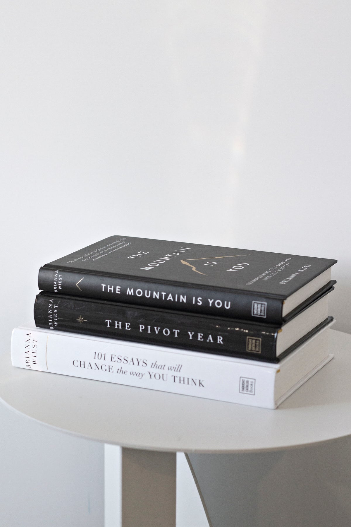 Three Brianna Wiest titles stacked on a round white pedestal table, spines facing out