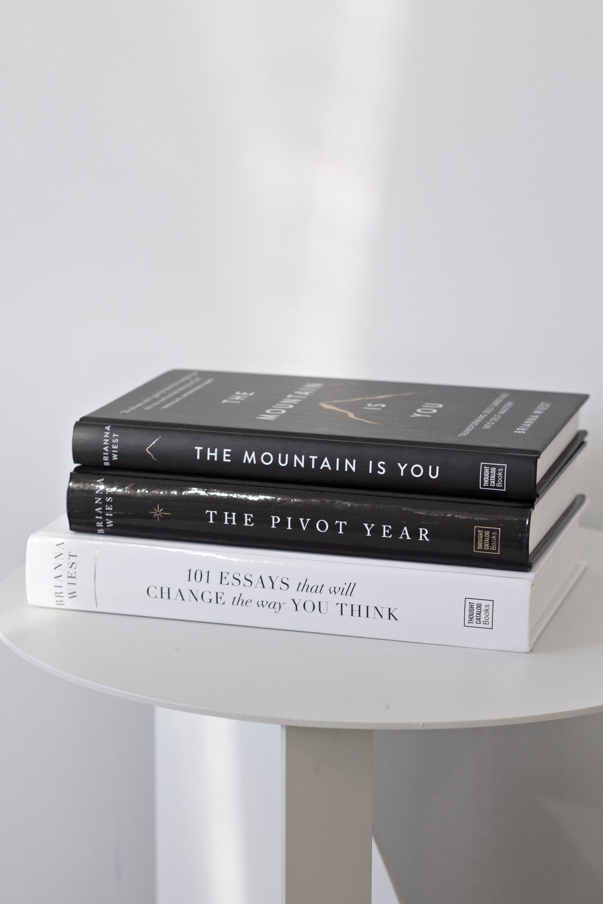 The same three titles stacked on a round white table, seen from a lower angle