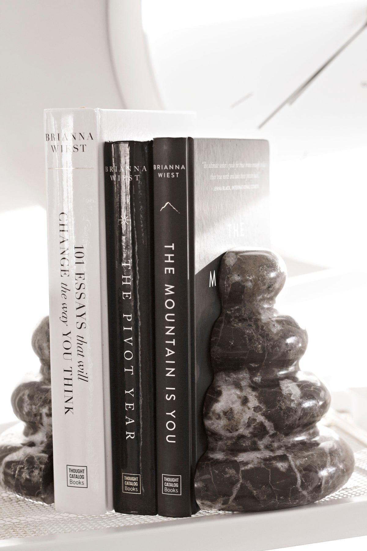 Three Brianna Wiest titles upright between dark marble pebble bookends, spines facing out