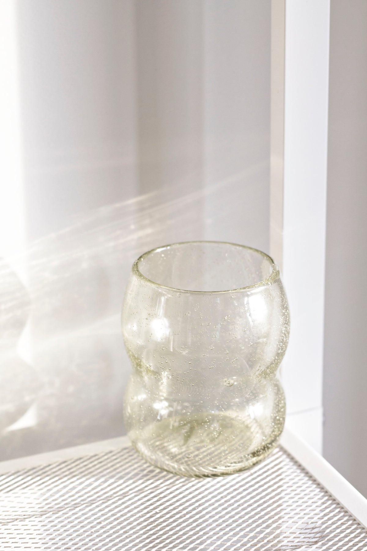 Light amber tumbler on a white mesh shelf in window light