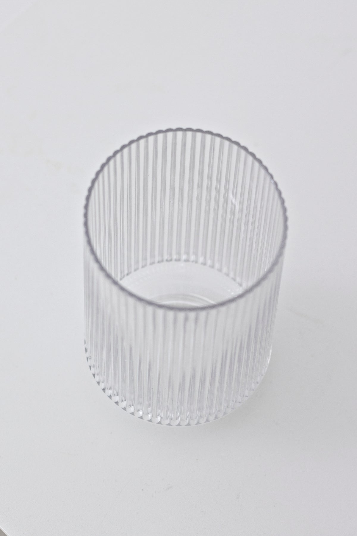Clear fluted tumbler photographed low and empty, showing the ribbed wall and rounded base