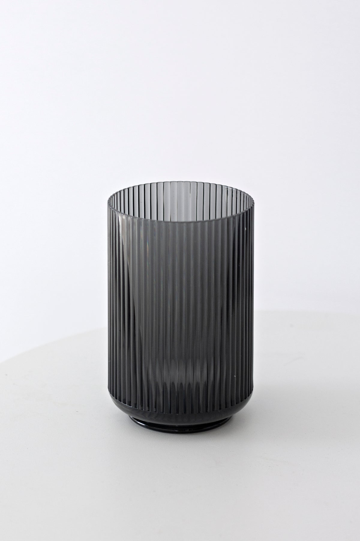 Smoke grey fluted tumbler standing alone on a white surface with a soft shadow