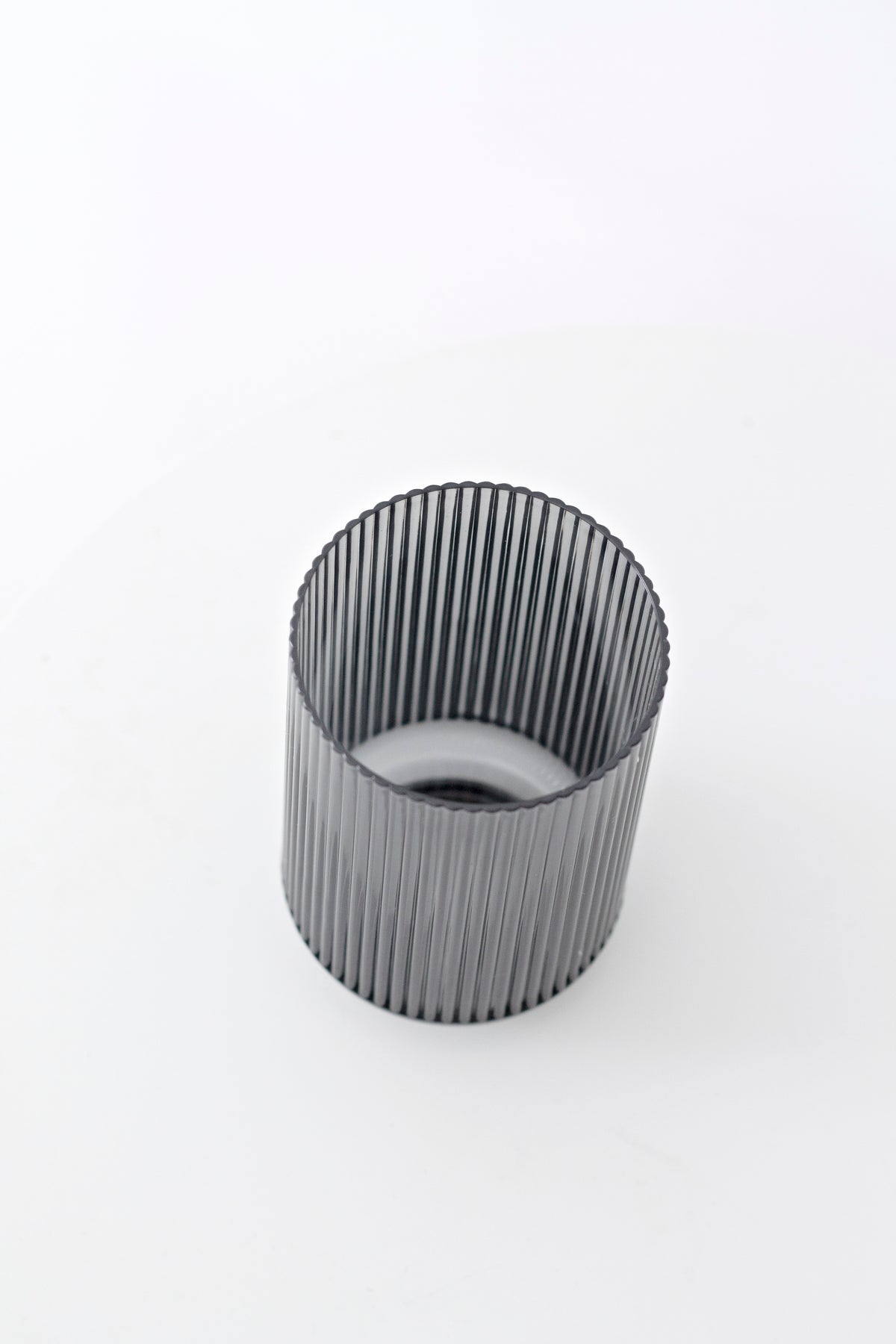 Smoke grey fluted tumbler tilted to show the ribbed interior and open rim