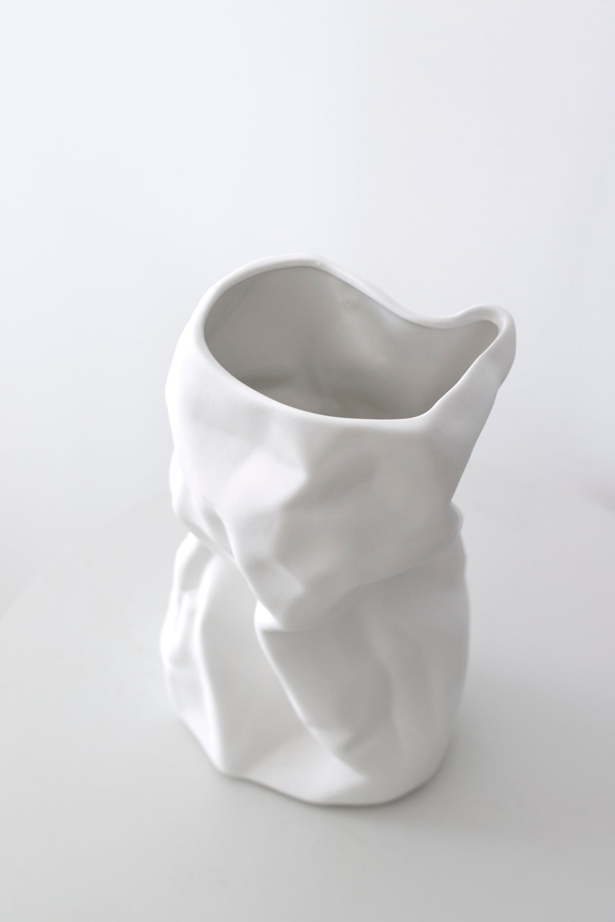 Close view of the white crumpled vase showing its pinched rim and soft folds