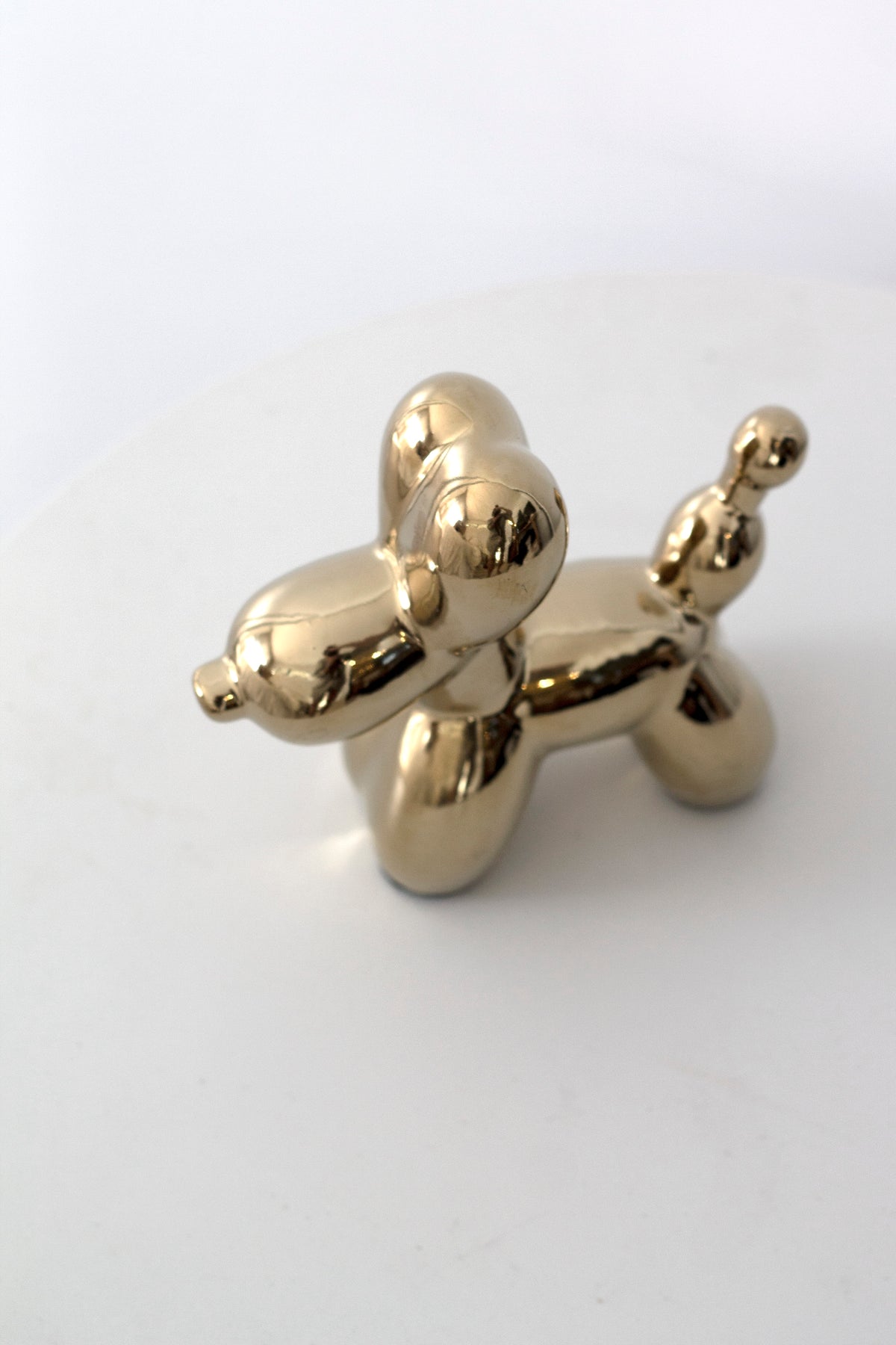 Gold electroplated balloon dog sculpture on a pale grey background