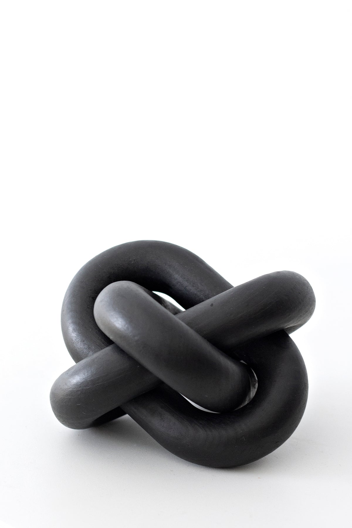 Black knot ornament, the three carved links in a matte black finish on white