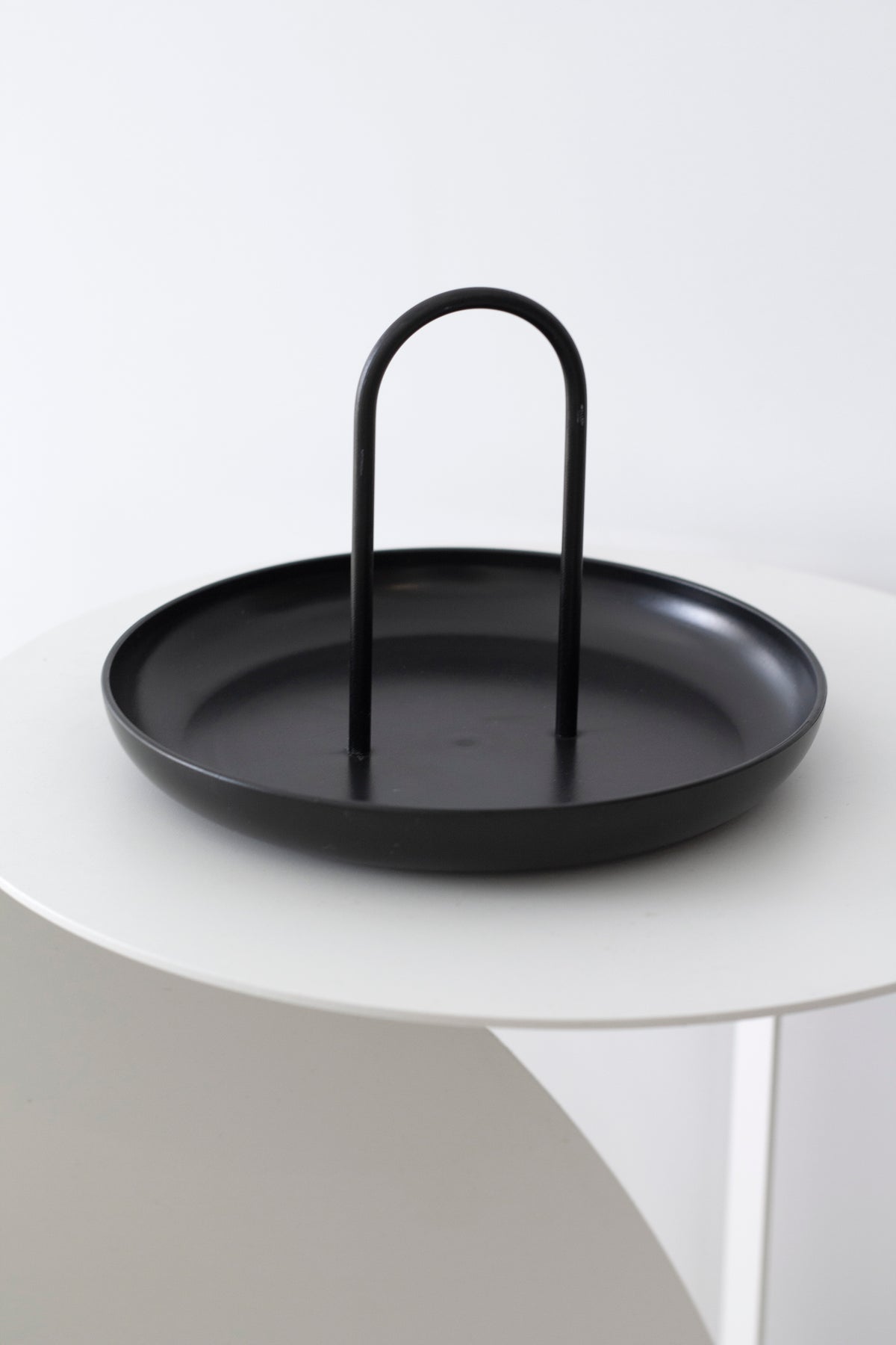 Black FIKA tray sitting on a white round side table against a plain wall