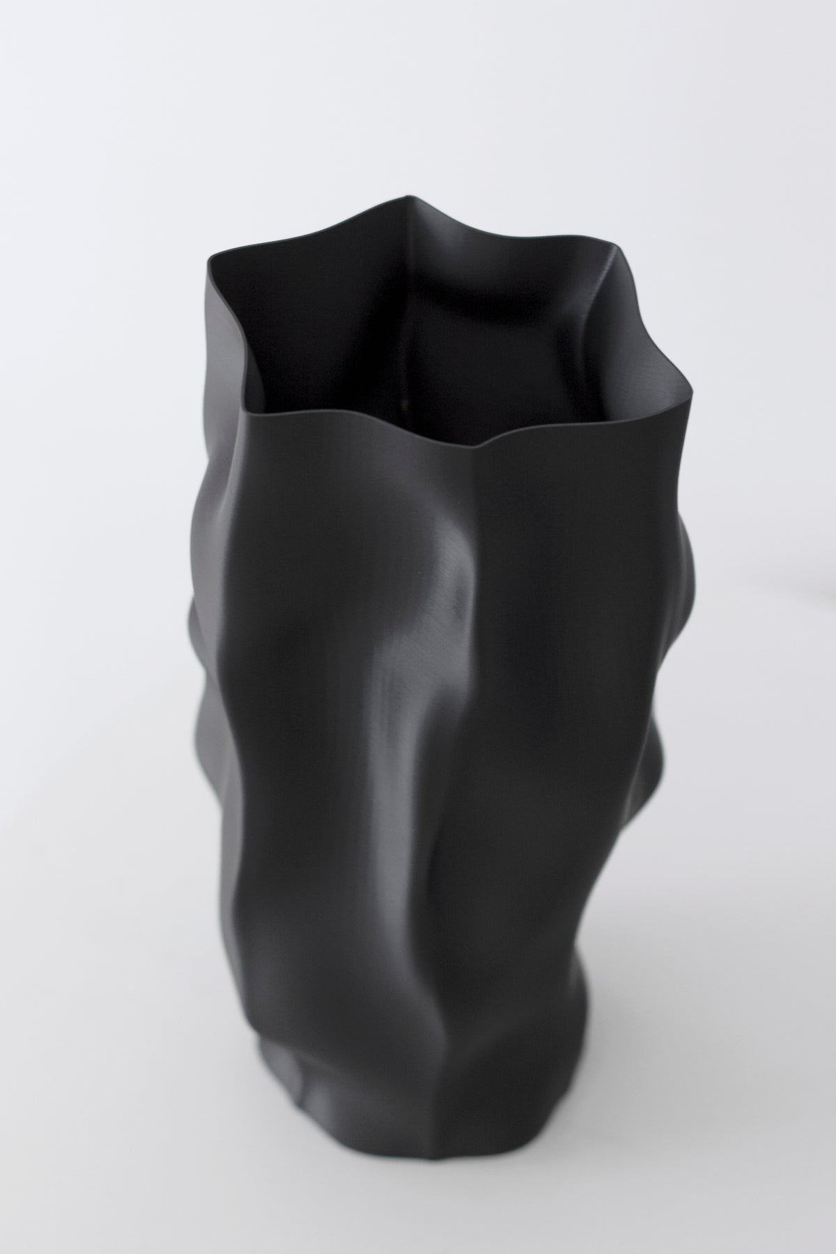 Skyler ripple vase in matte black, the folded column shown at an angle against white