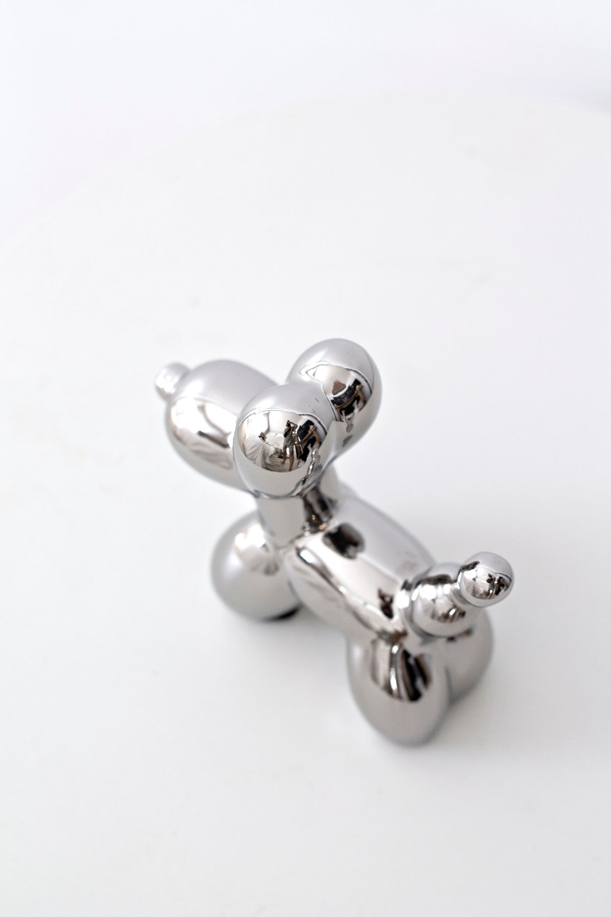 Silver ceramic balloon dog sculpture, three-quarter view on white