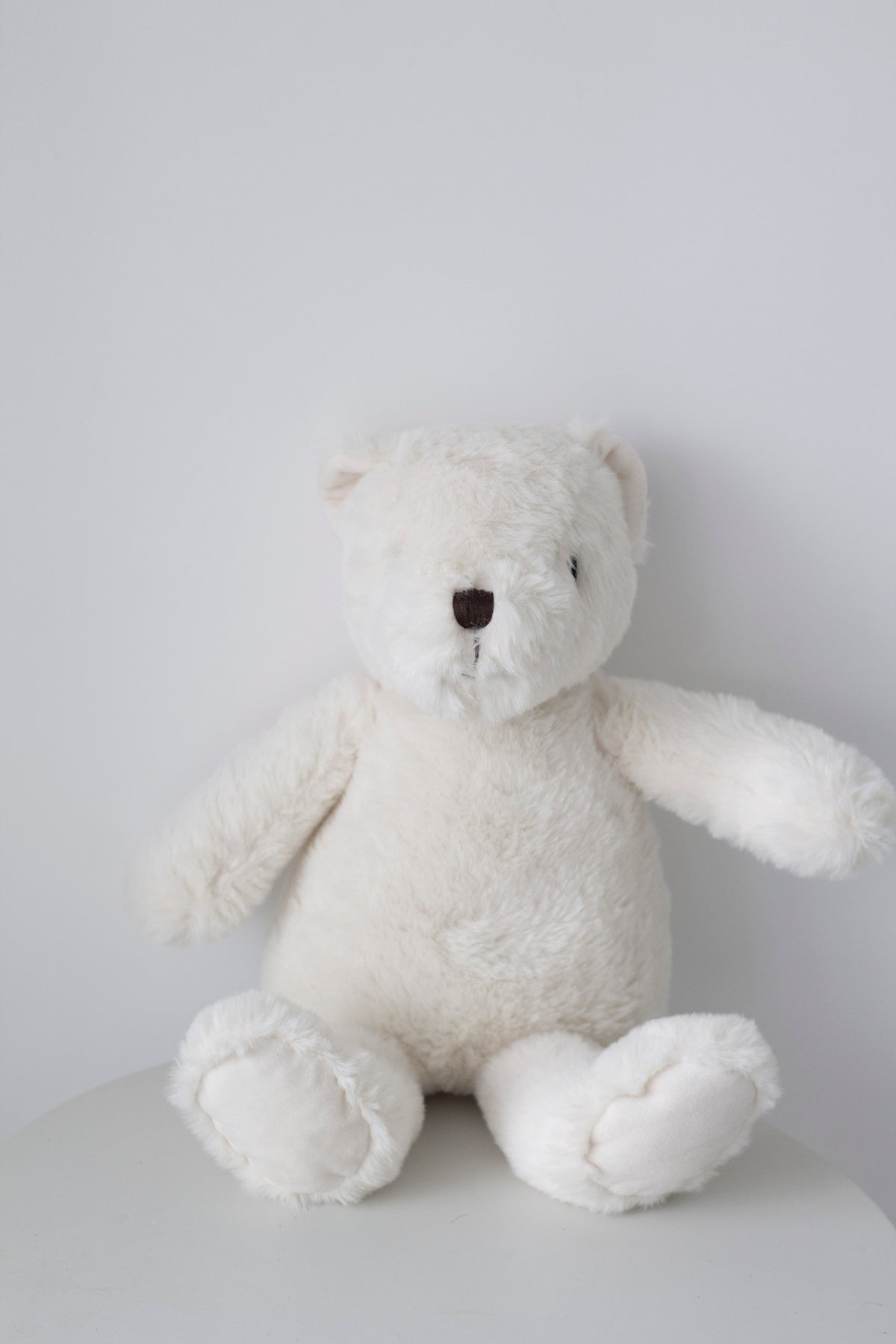 Warm White Flopsy Bear sitting on a white table, front view