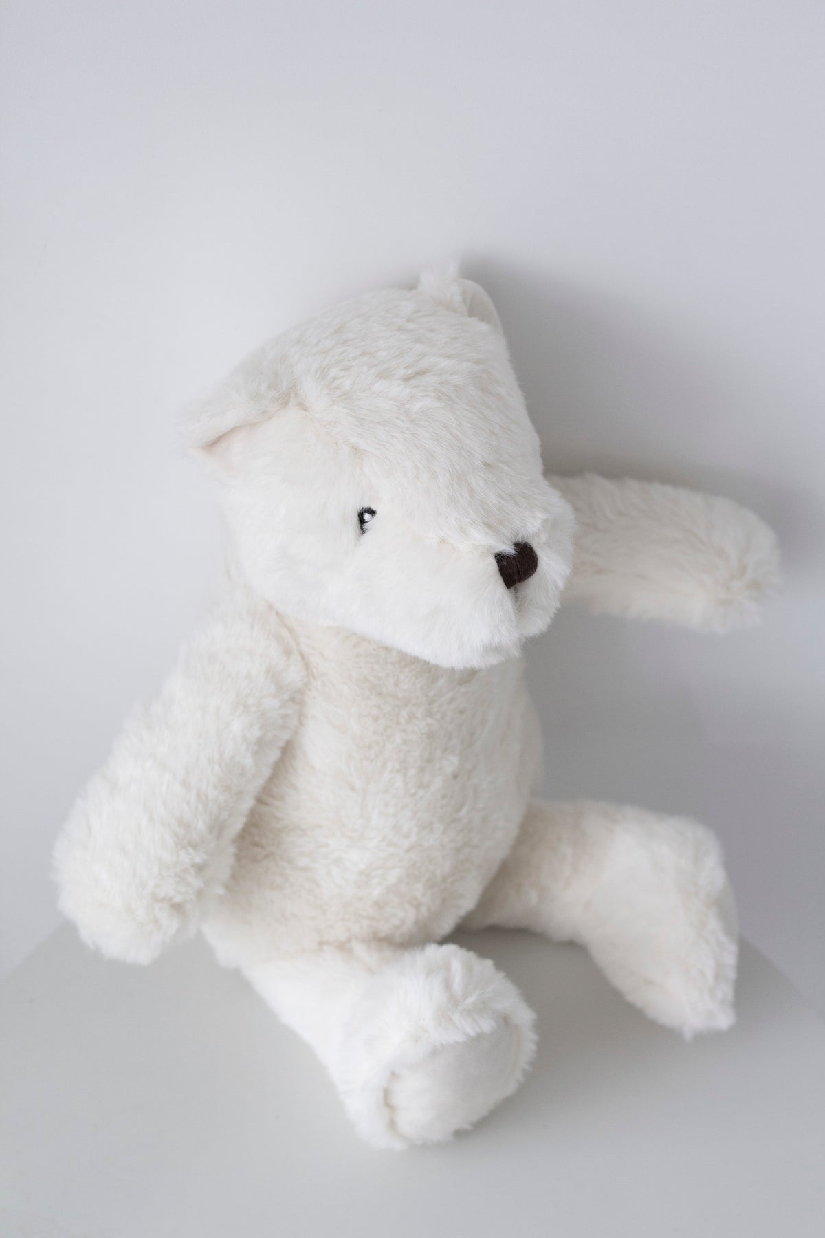 Warm White Flopsy Bear sitting against a pale grey background, side angle