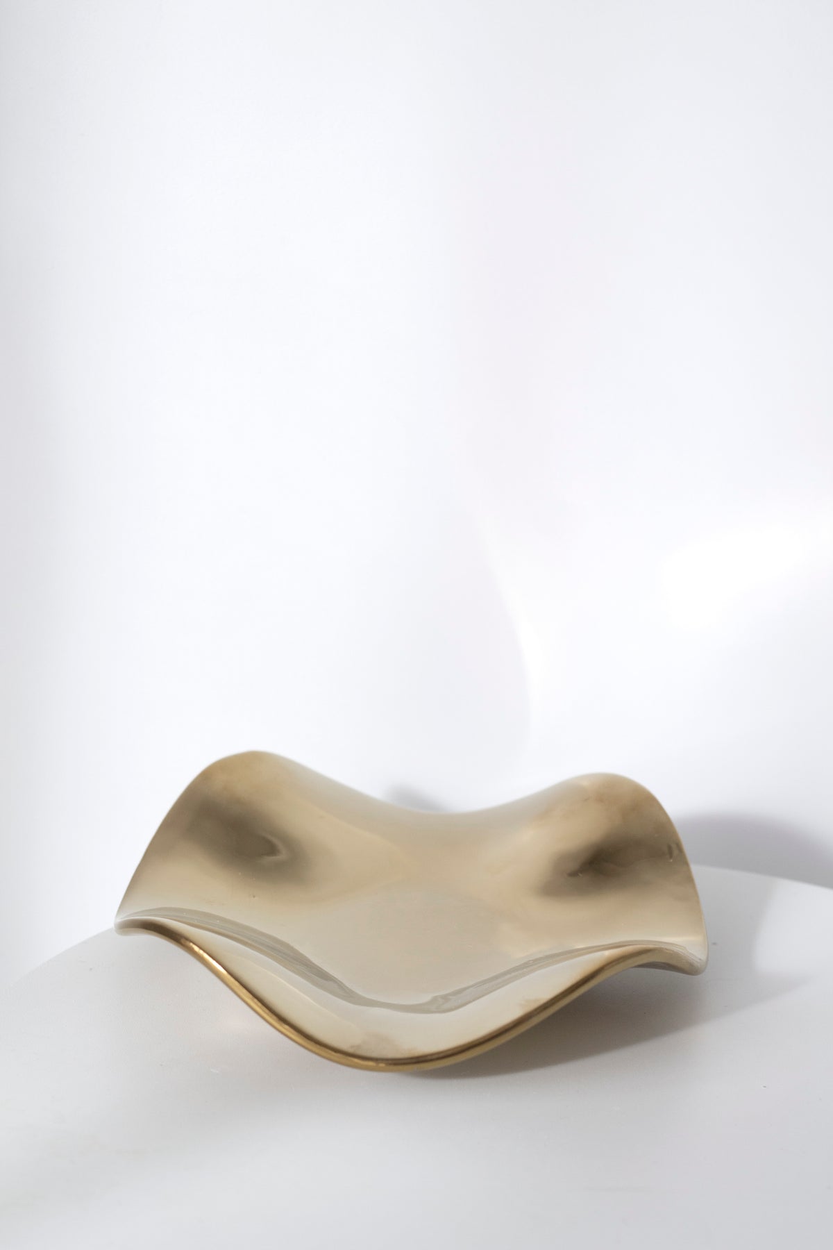 Pale gold wave tray photographed straight on, showing the deep curve of the wave form