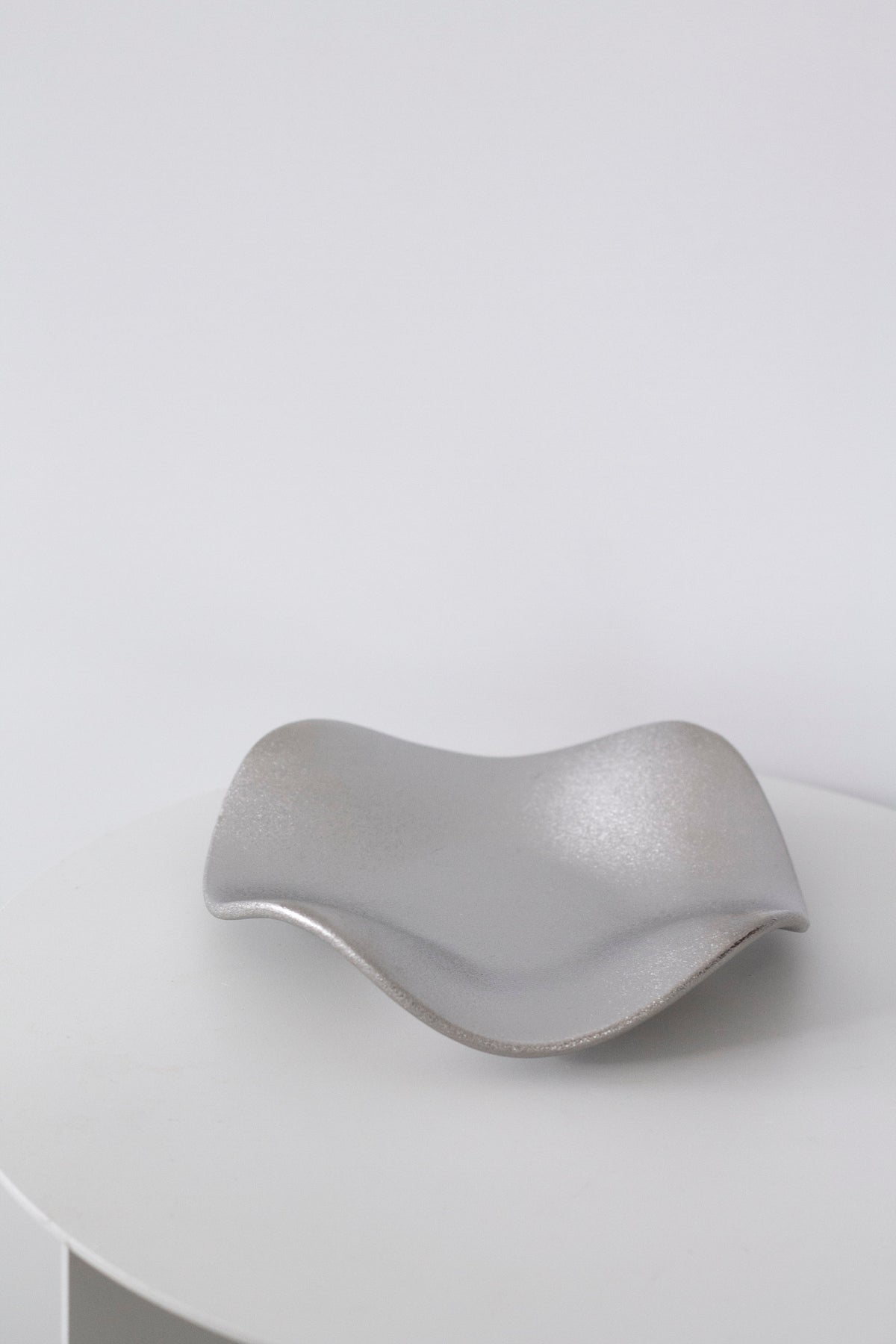Silver wave tray from the front on a white table, showing the low wave profile of the dish