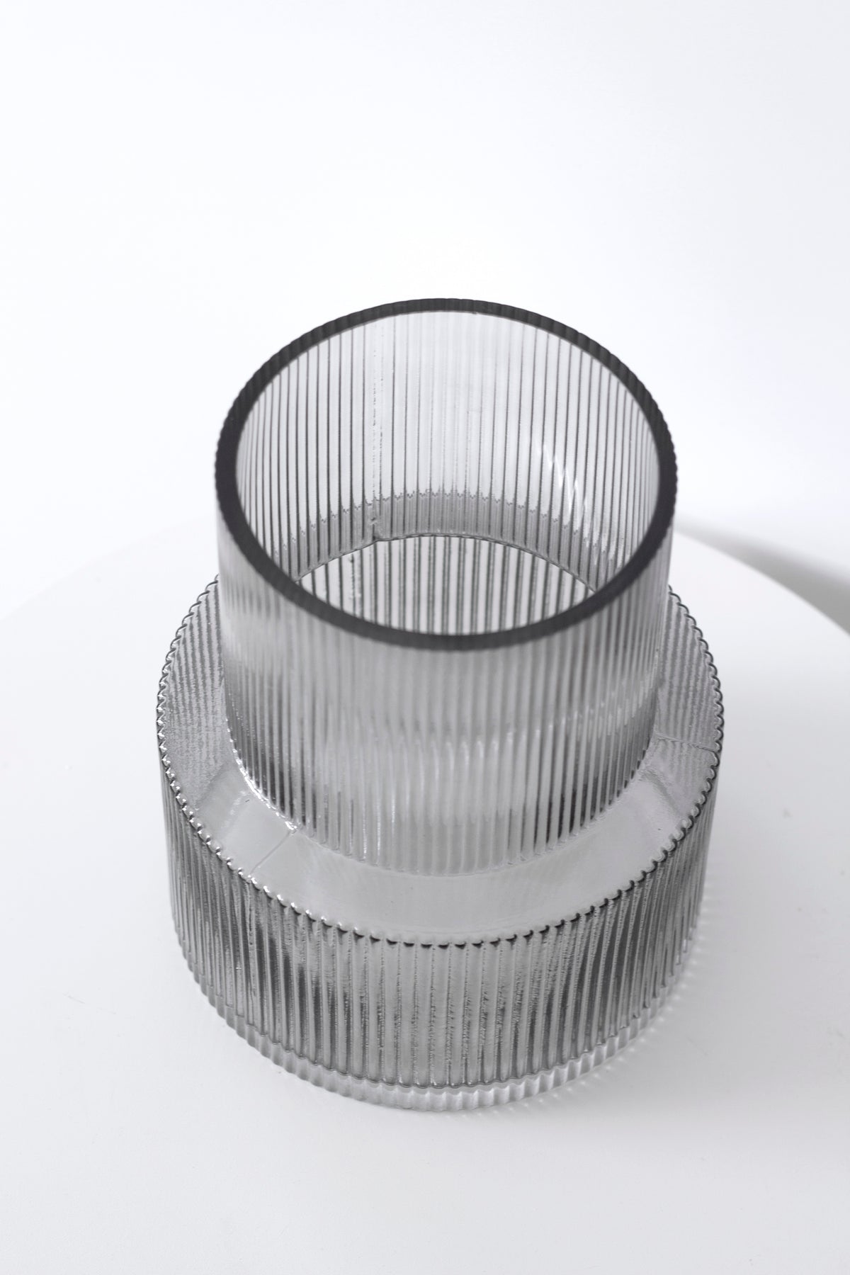 Smoke colourway of the ribbed vase viewed from above, grey tinted glass on a white surface