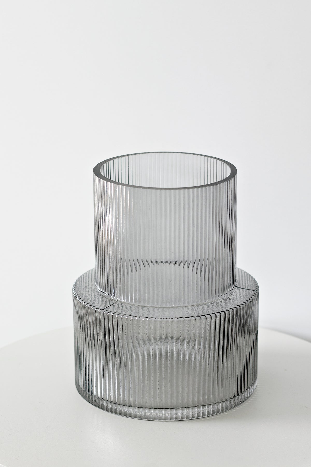 Smoke ribbed glass vase photographed straight on, showing the stepped silhouette in grey glass