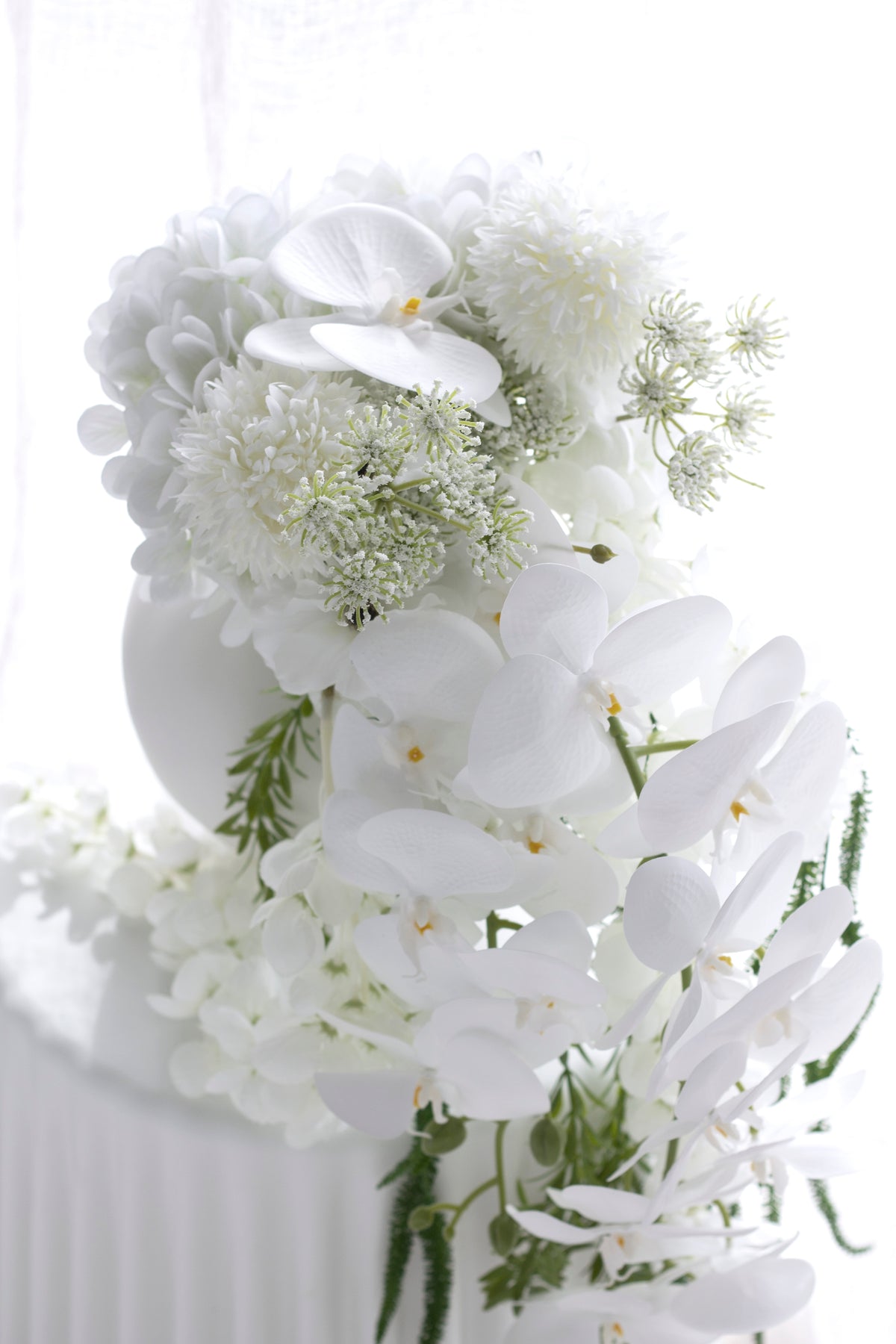 Close view of the bouquet's white orchid blooms and hydrangea heads in bright backlight
