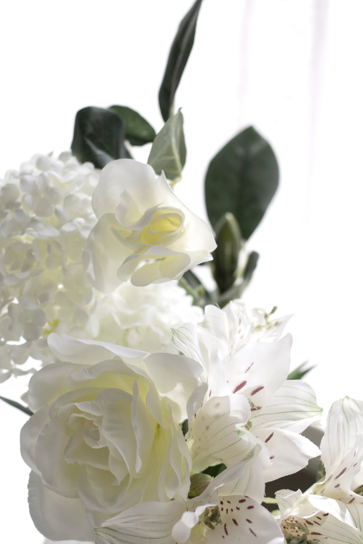 White gardenia layered with hydrangea and small white blossoms in a close arrangement