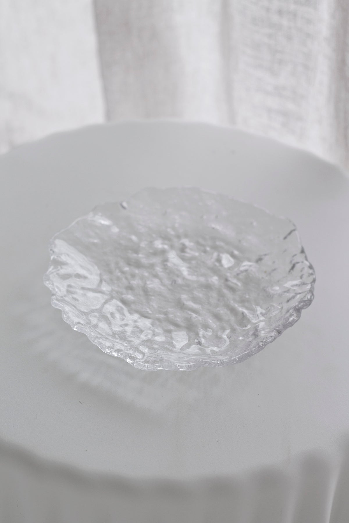 Glacier glass tray beside a frosted glass vessel on a pale ledge