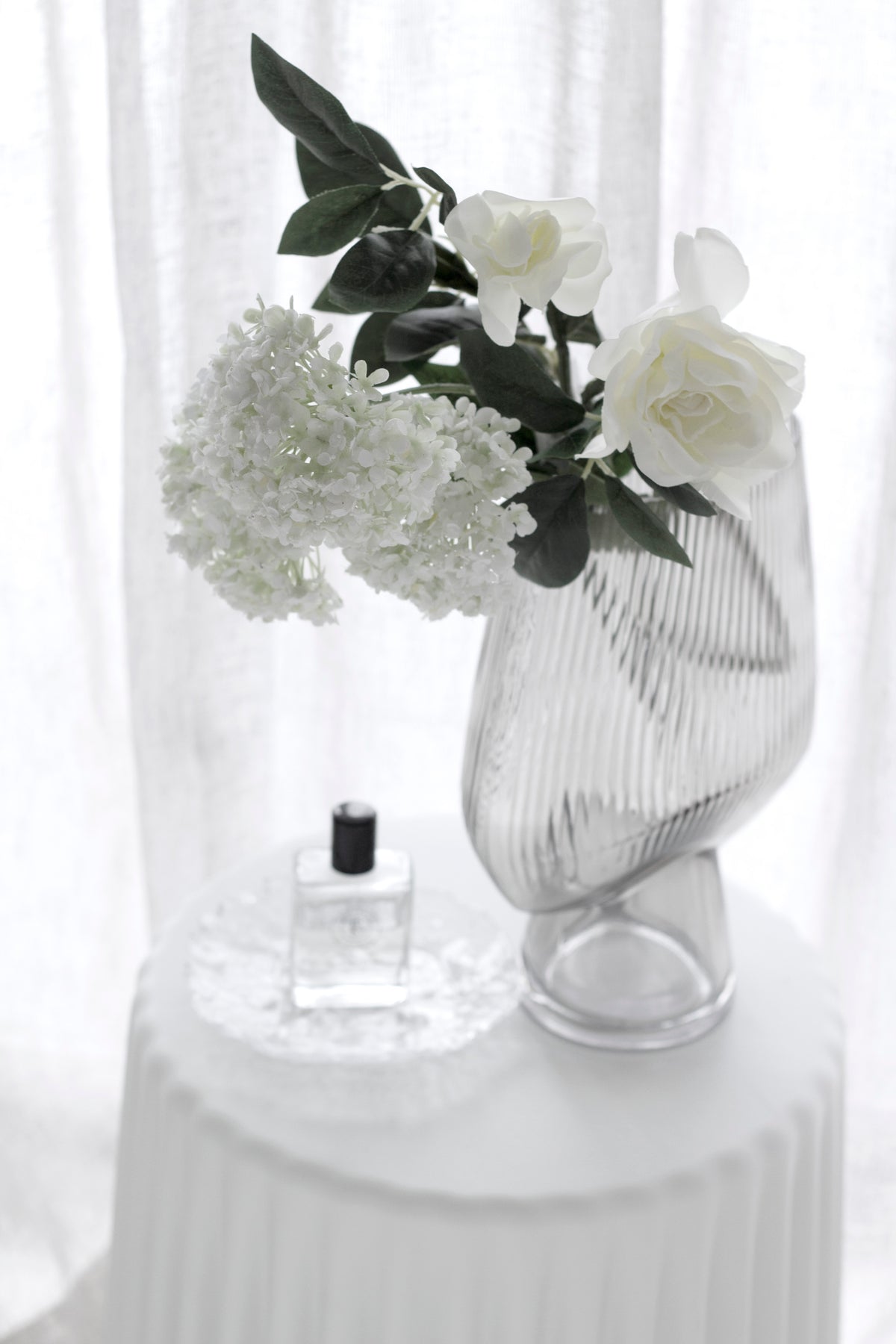 Gardenia and white hydrangea in a smoked ribbed vase on a fluted pedestal