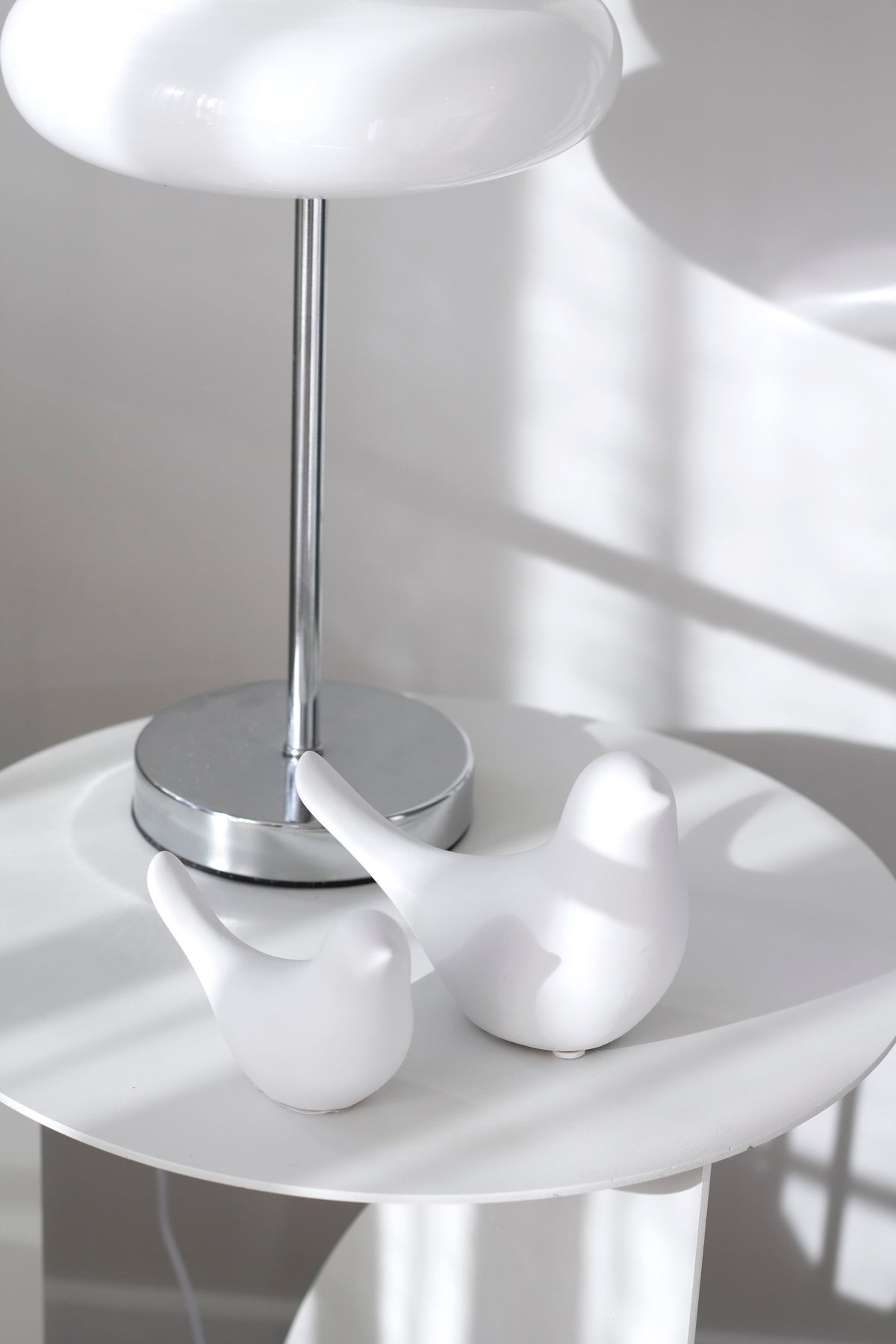 White Della doves on a round white table beneath a silver lamp