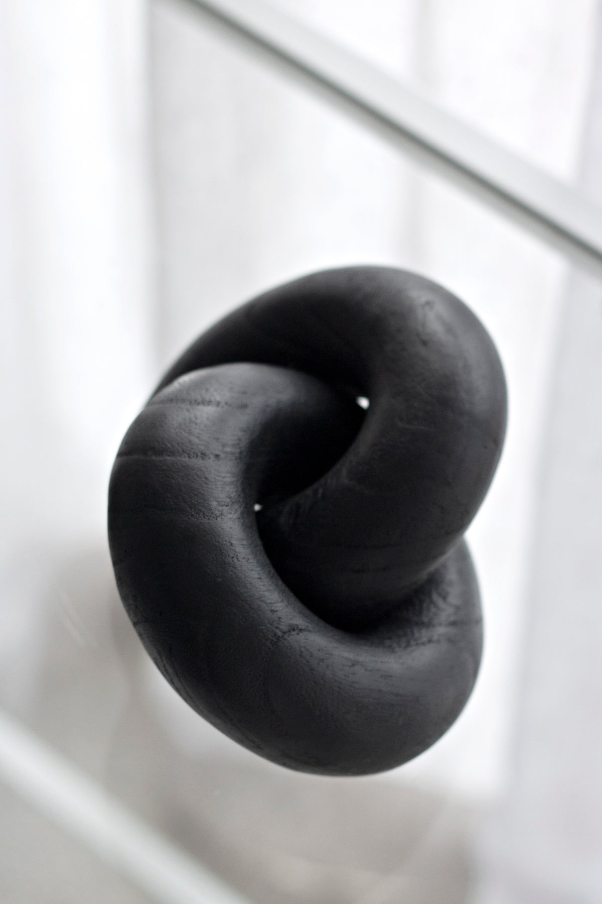 Black wooden knot sculpture from above on a white ledge