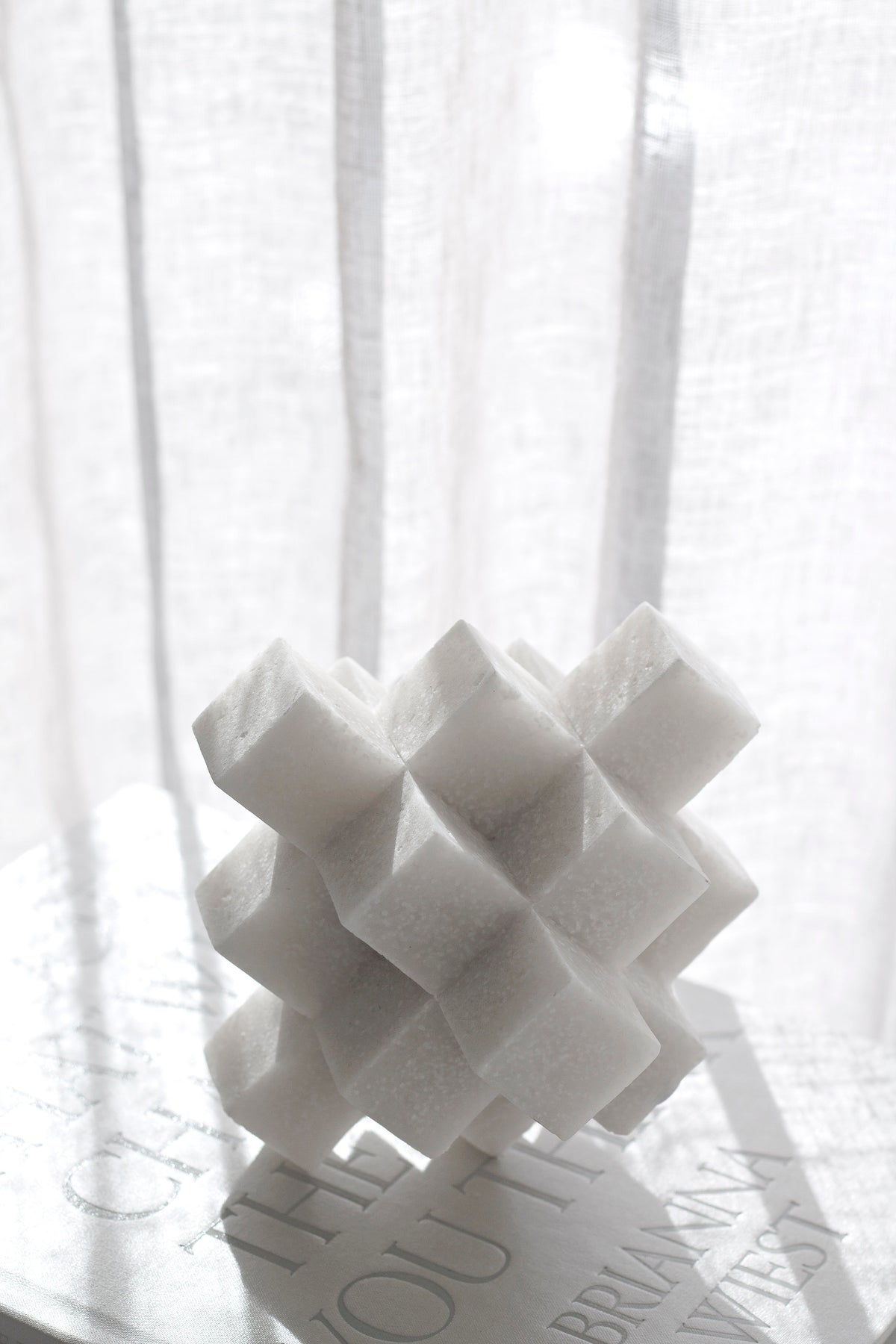 White Cubism sculpture against a sheer curtain, cubes catching the light