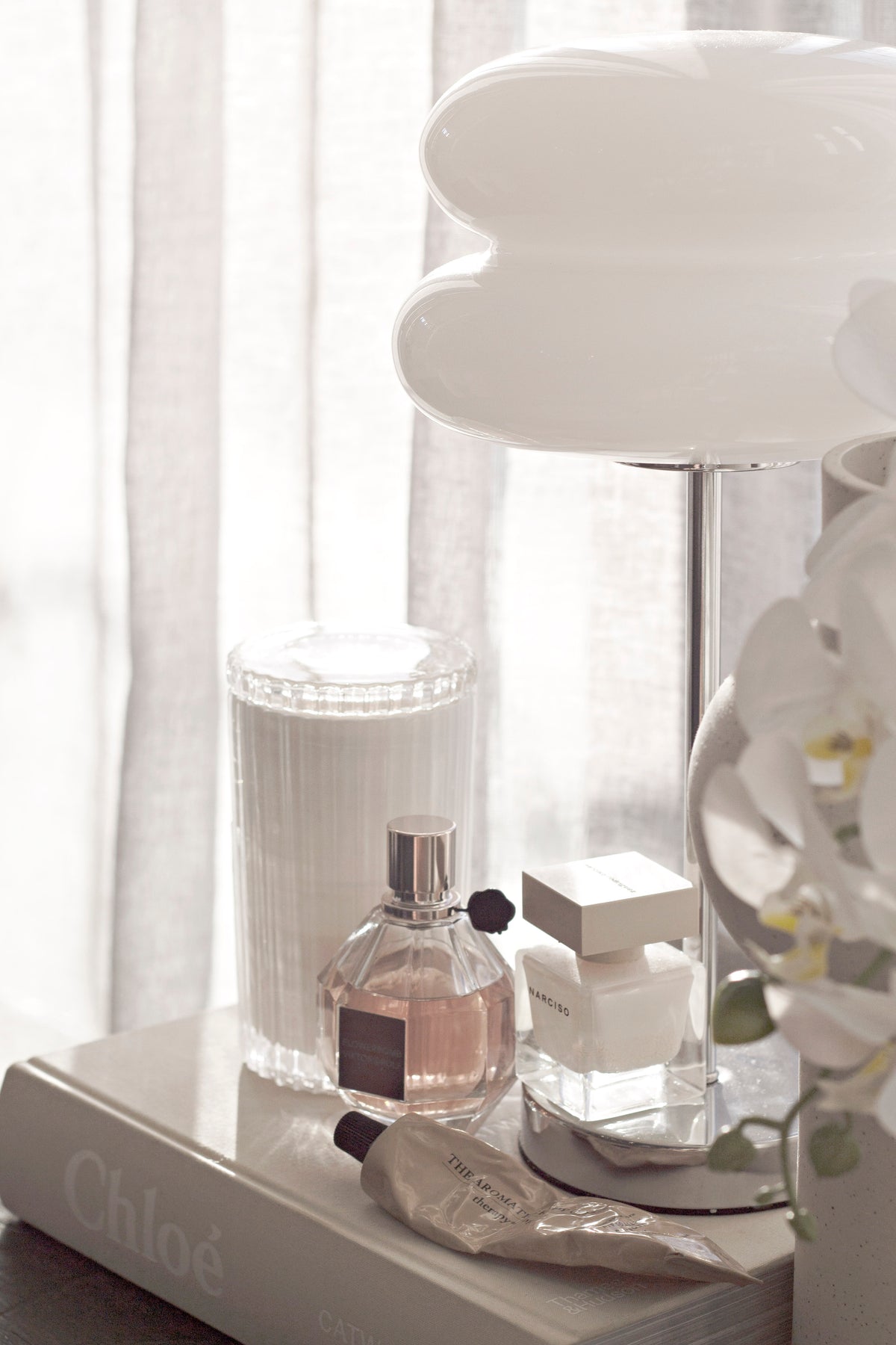 Celebration candle on a dresser with perfume bottles and a white lamp