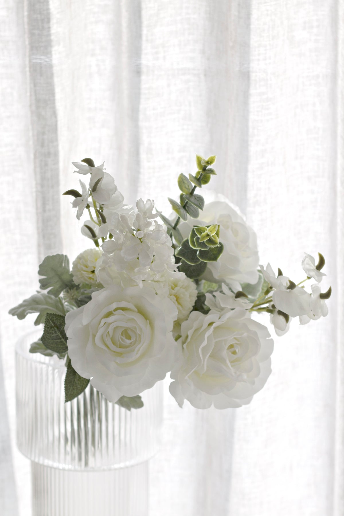 White faux bouquet with grey-green foliage in soft daylight