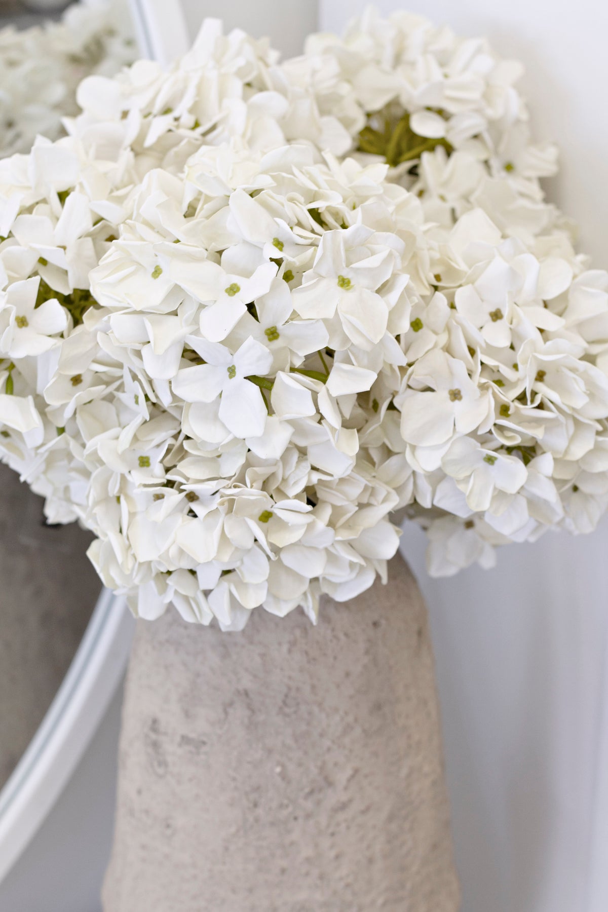 Cream faux hydrangeas in a textured stone vase