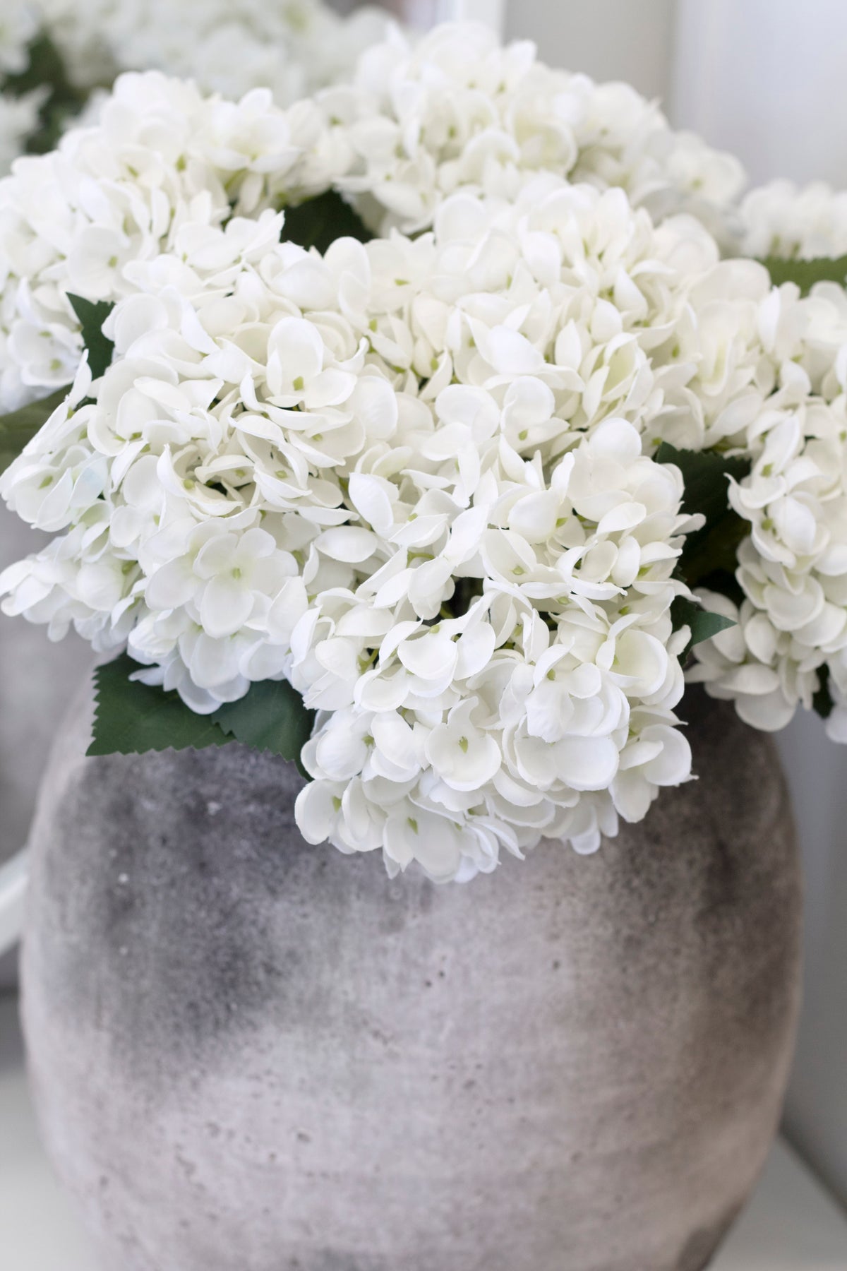 Close view of the hydrangeas filling the mottled grey stone urn