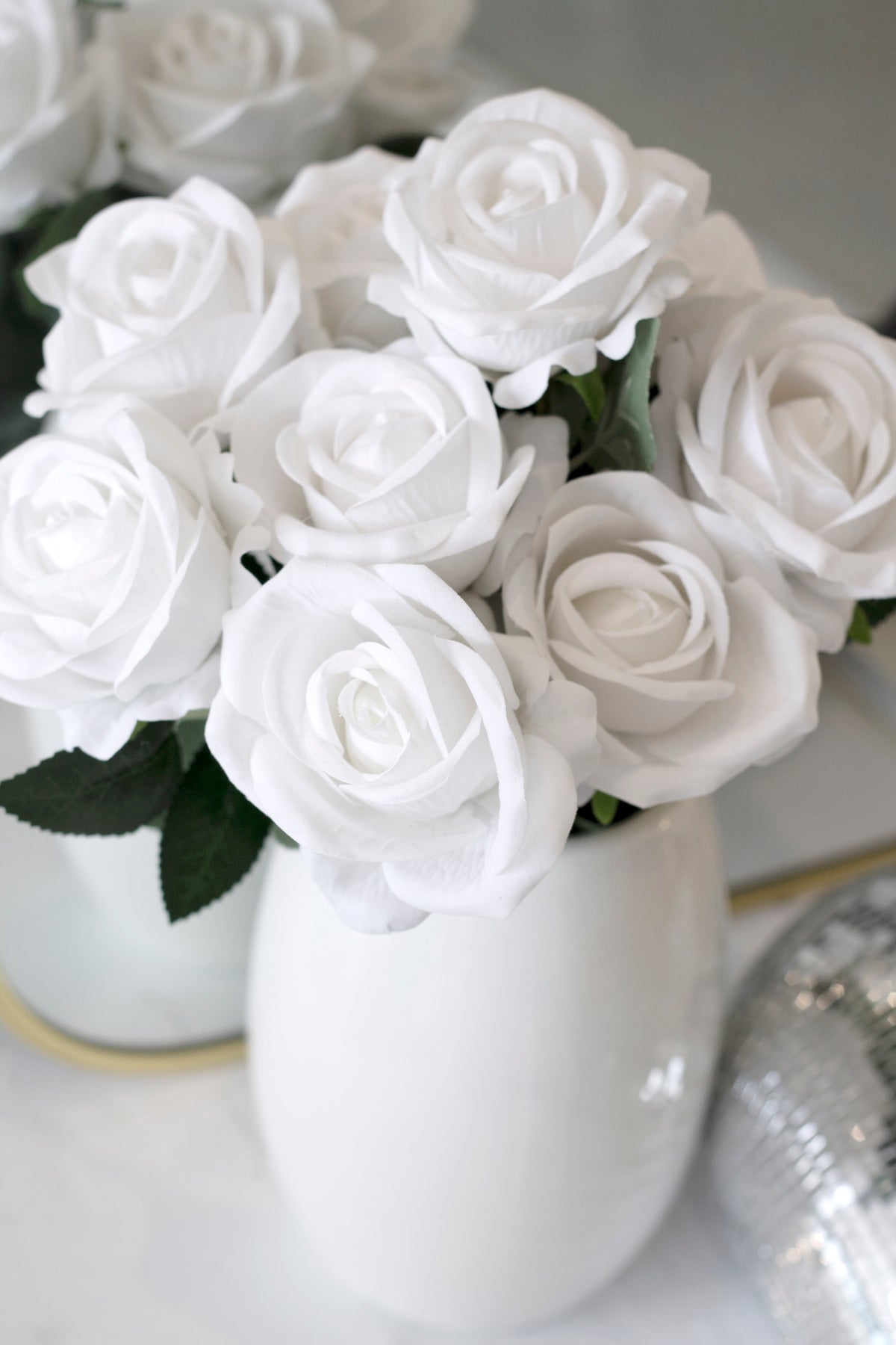 White faux roses massed in a white ceramic vase