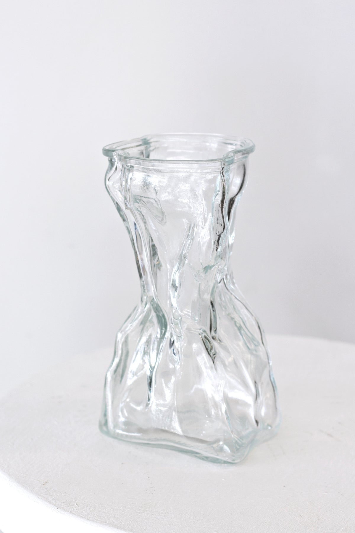 Clear crinkle vase standing straight on against a plain white surface