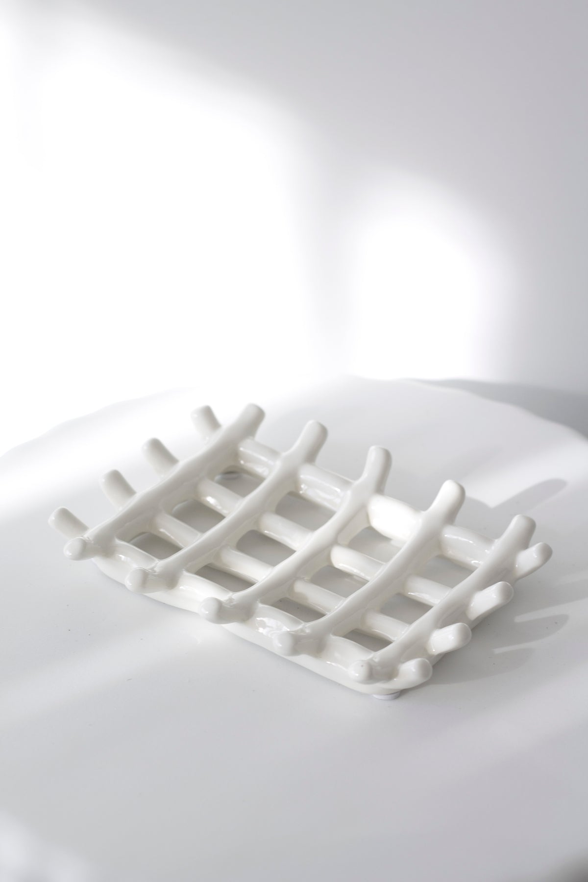 Edie soap dish on a rounded white ledge, the raised feet lifting it clear