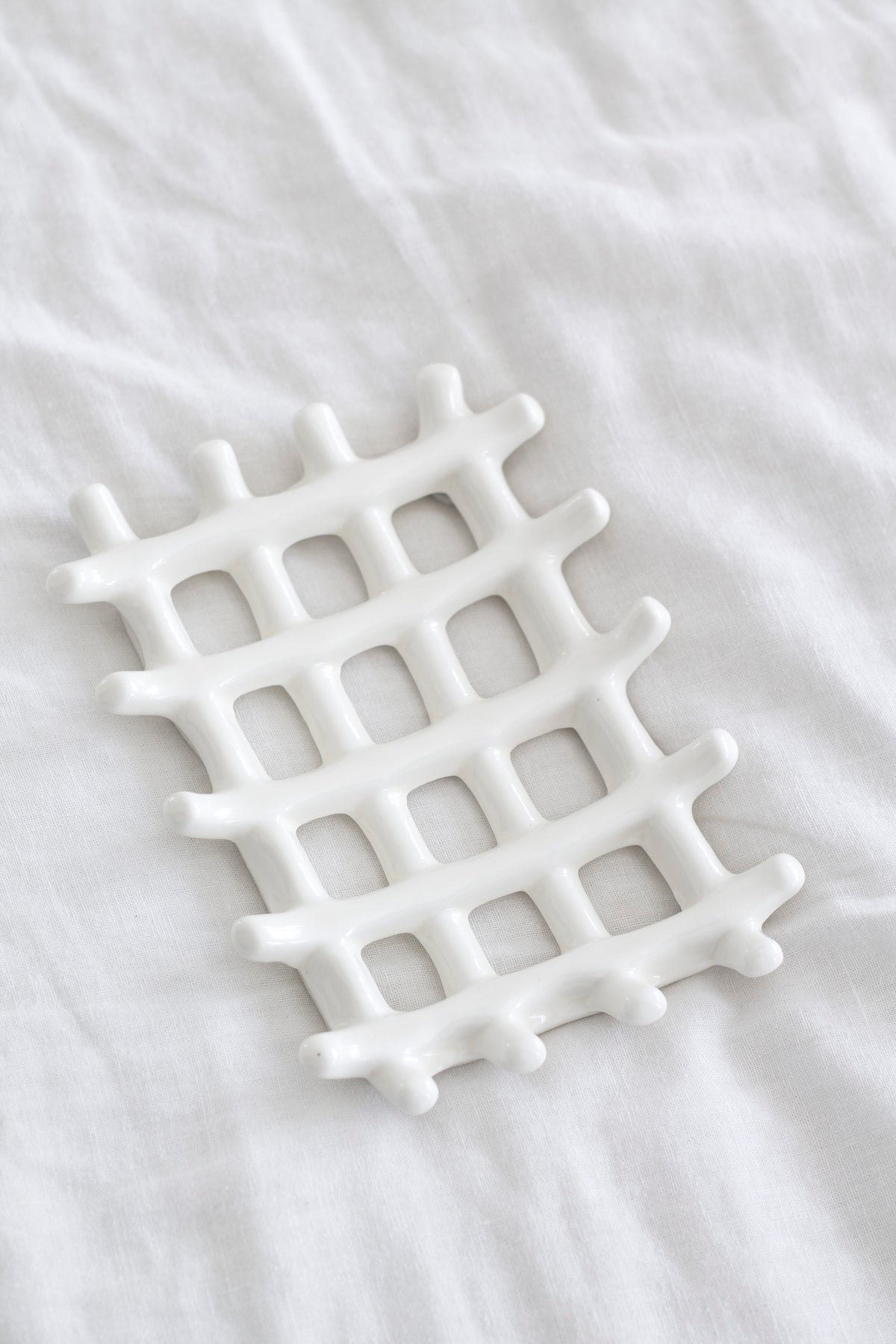 Soap dish resting on crumpled white linen, seen from above