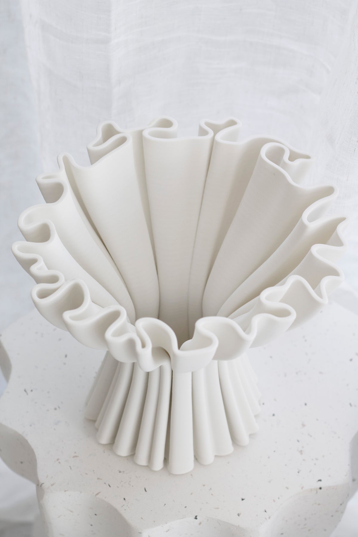White Cleo compote vase seen from above, showing the pleated ridges and ruffled rim against a sheer curtain