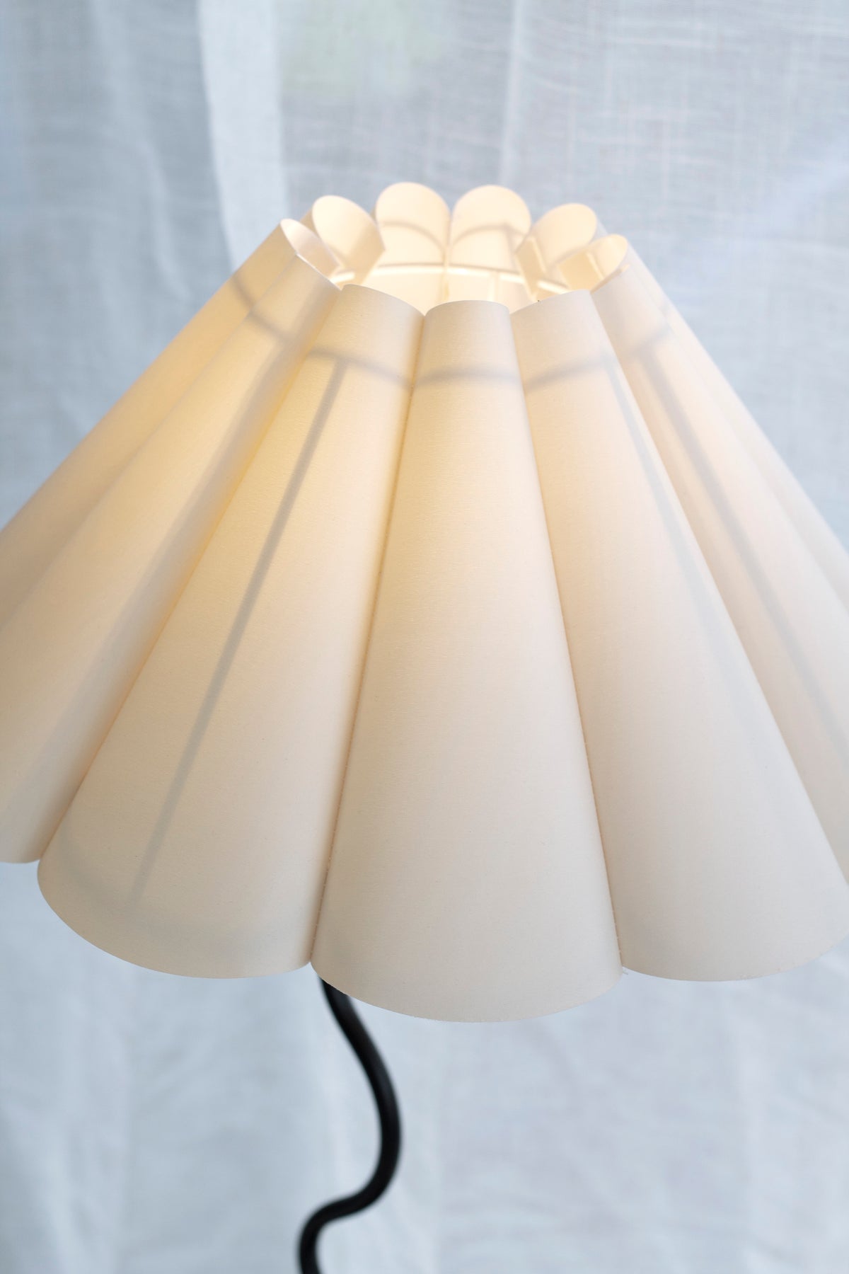 Close-up of the pleated off-white fluted shade on the black Wavy table lamp against window light