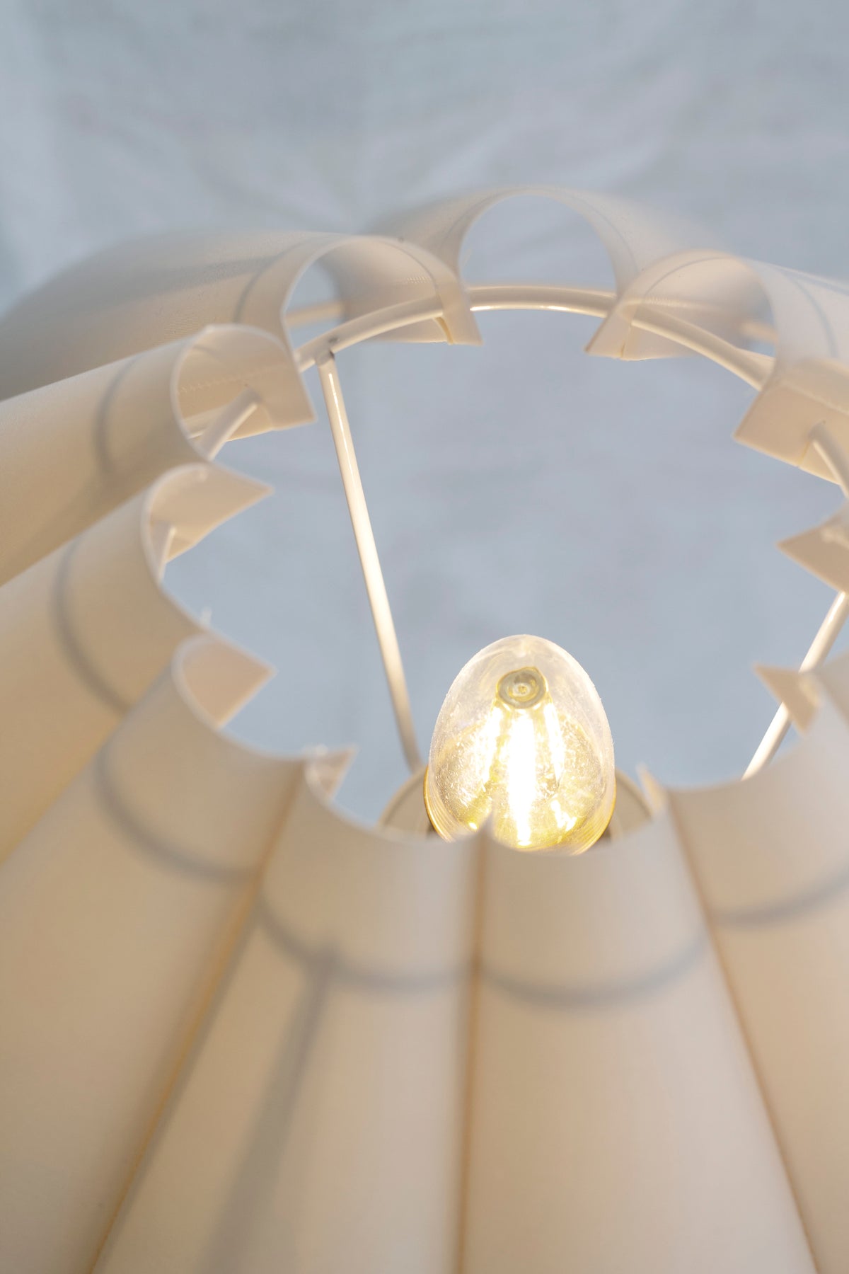 Detail of the lit bulb and scalloped inner edge of the Wavy table lamp's pleated shade