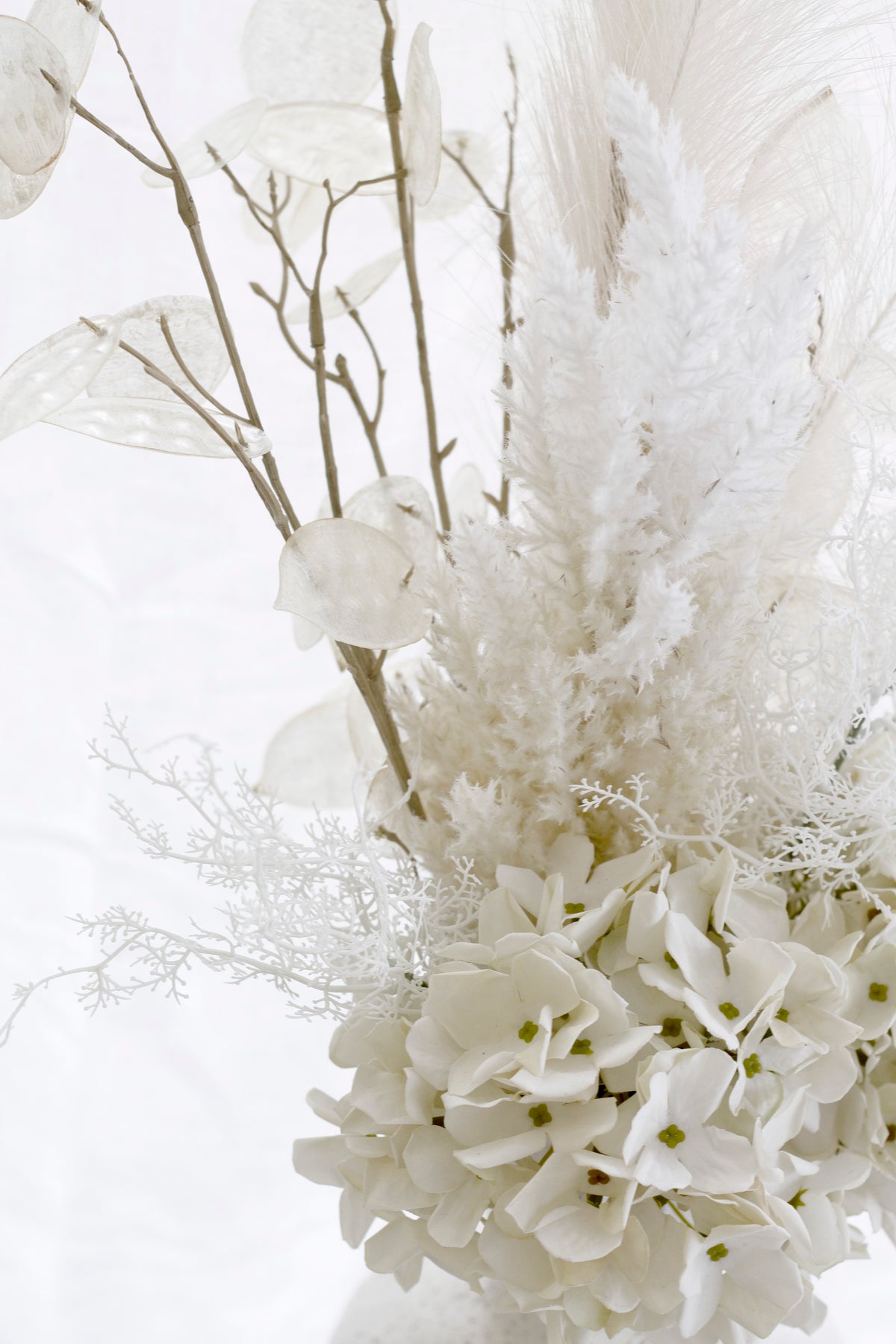The cream arrangement wider, fine branches and dried sprays among the hydrangea