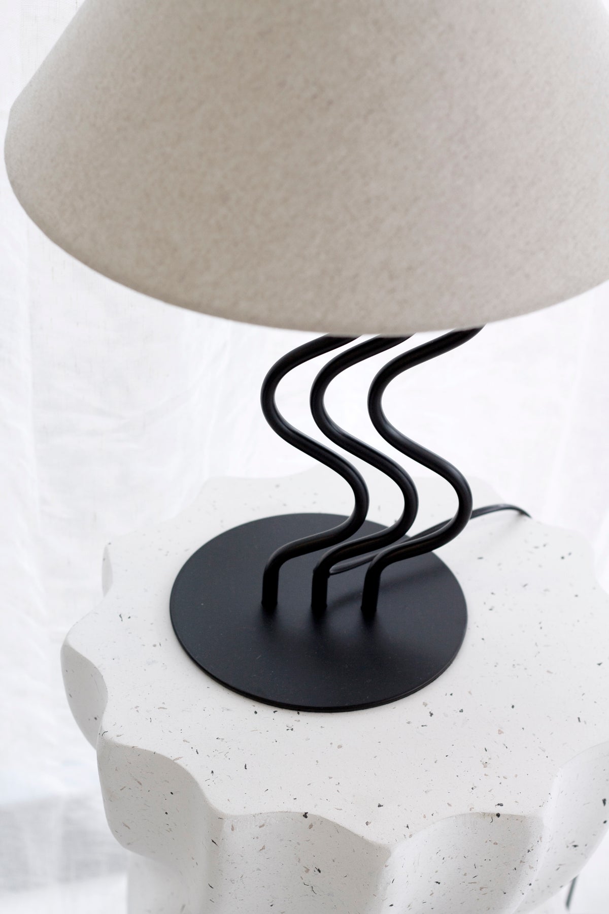 Low view of the Surge lamp on a white fluted pedestal