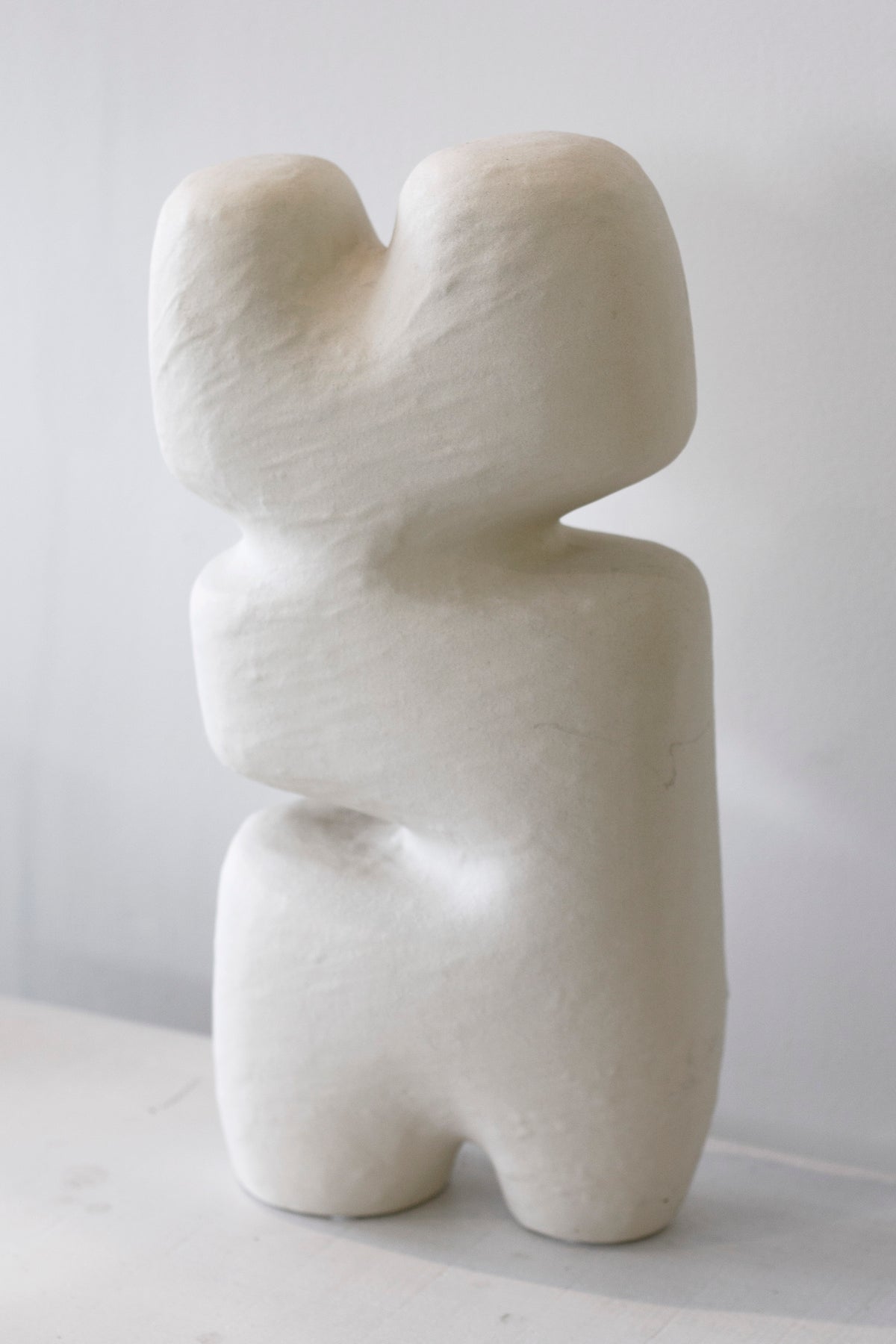 Block sculpture front on against a plain wall, the notched arms and legs in view