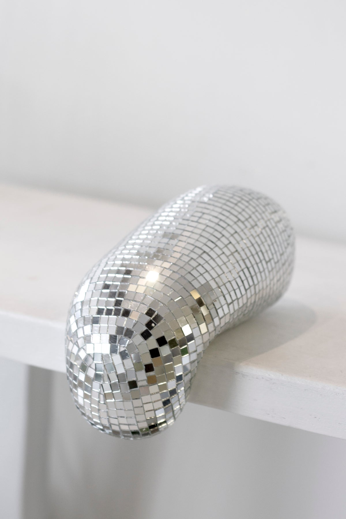 Small melting disco ball on the corner of a white ledge