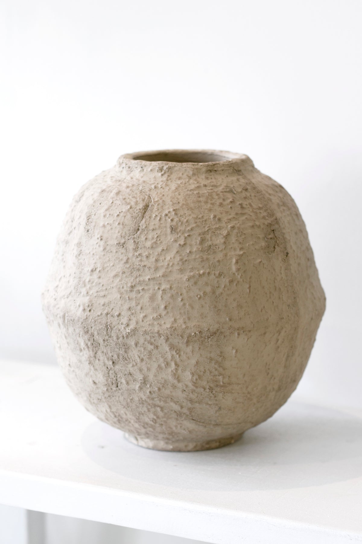 Joni sand terracotta vase standing empty on a white surface against a pale wall