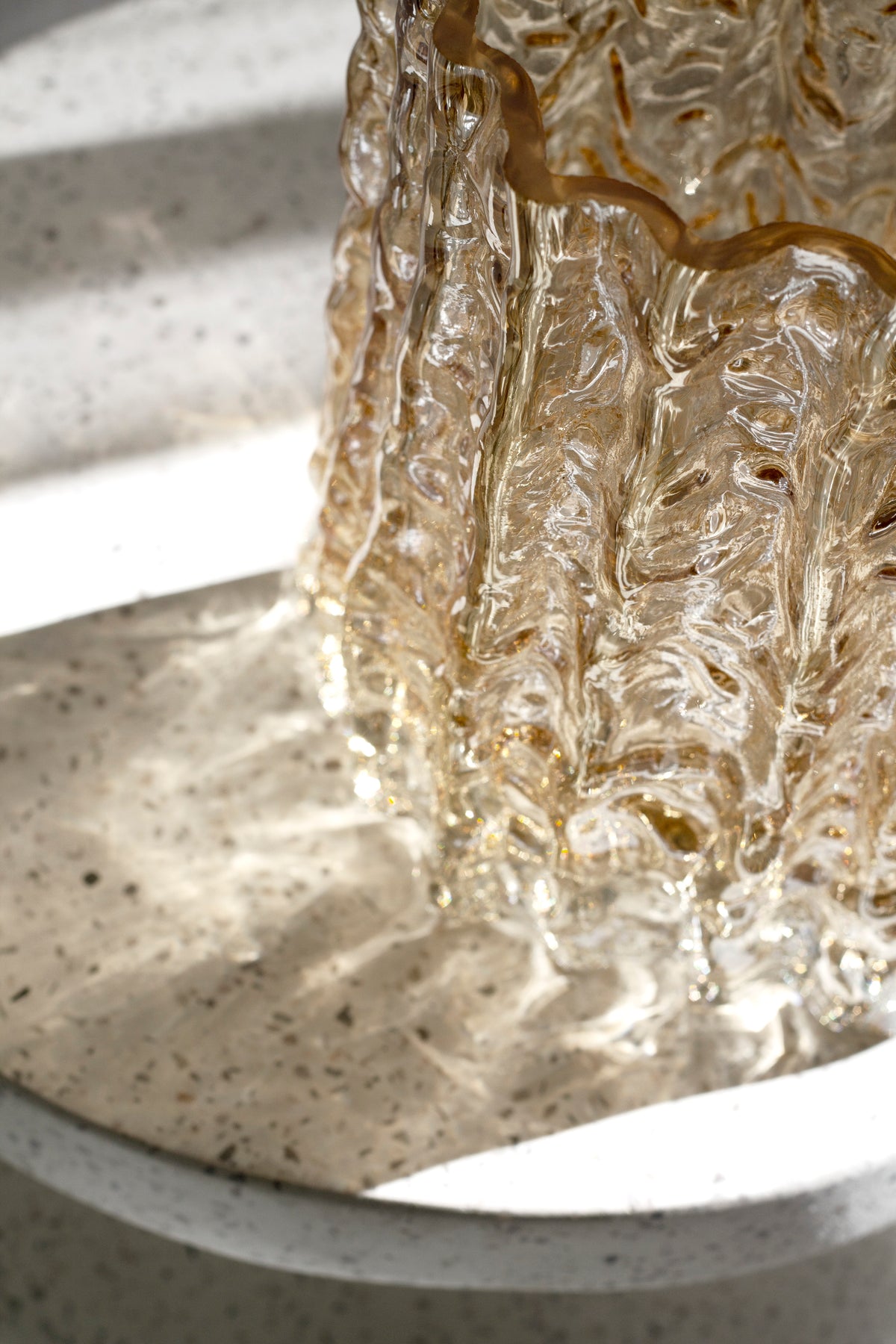 Gold Glacier vase base on a stone pedestal, photographed from a lower angle