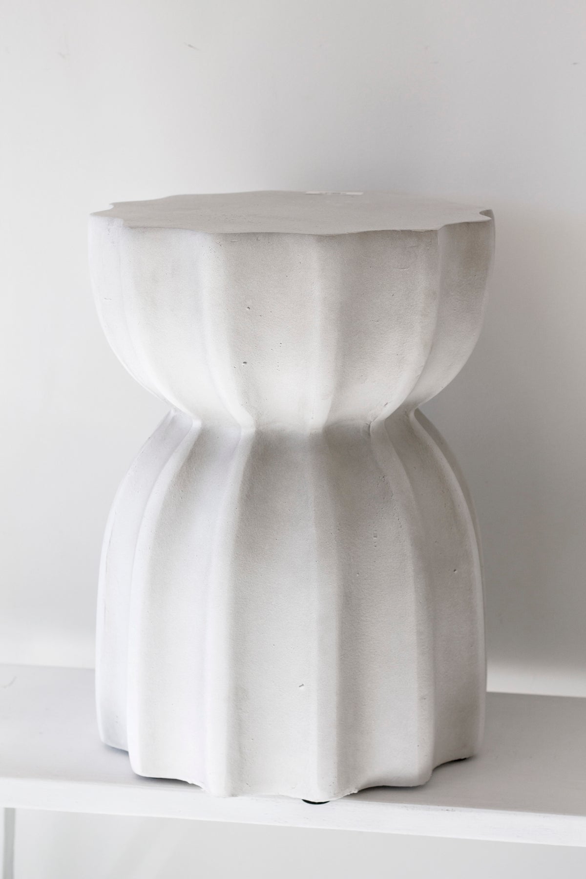 Fluted side table in fleck white on a pale floor against a plain wall