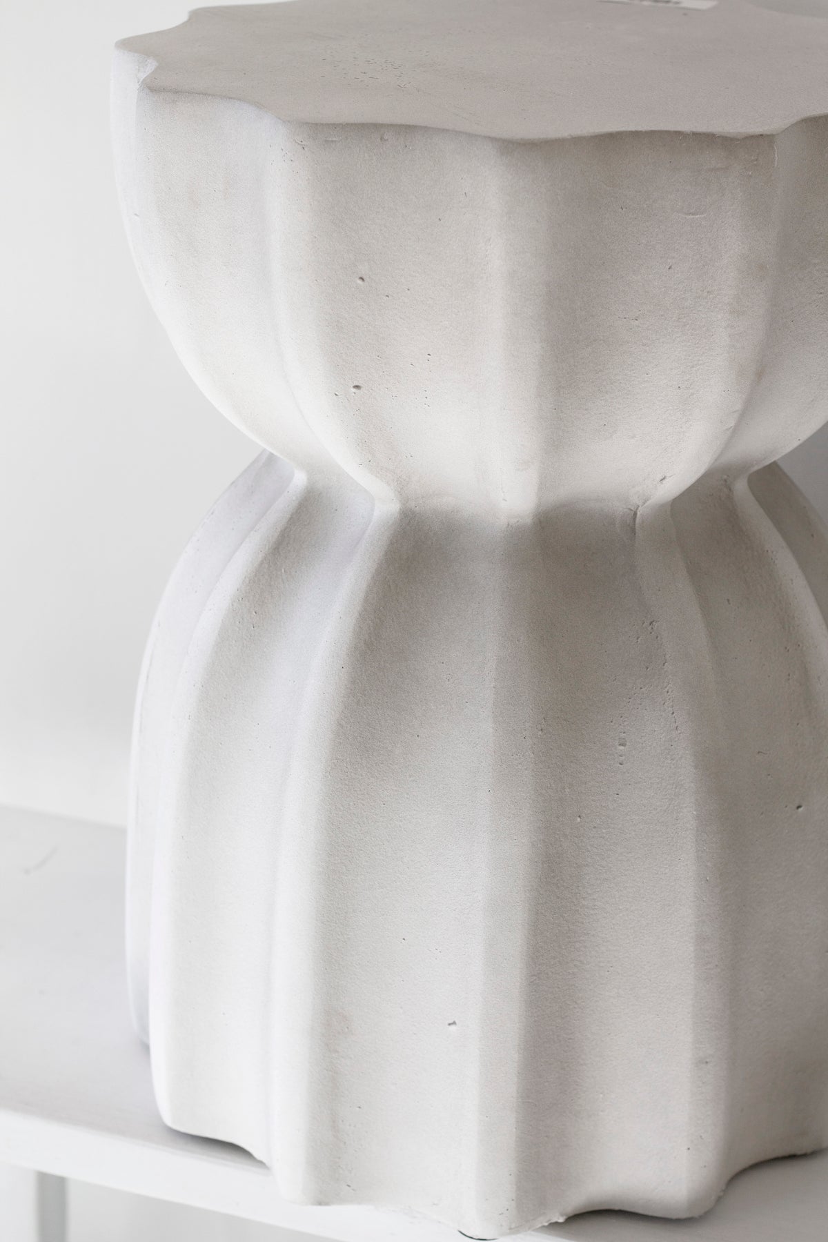 Close on the fluted table's scalloped column and the curve where it meets the top