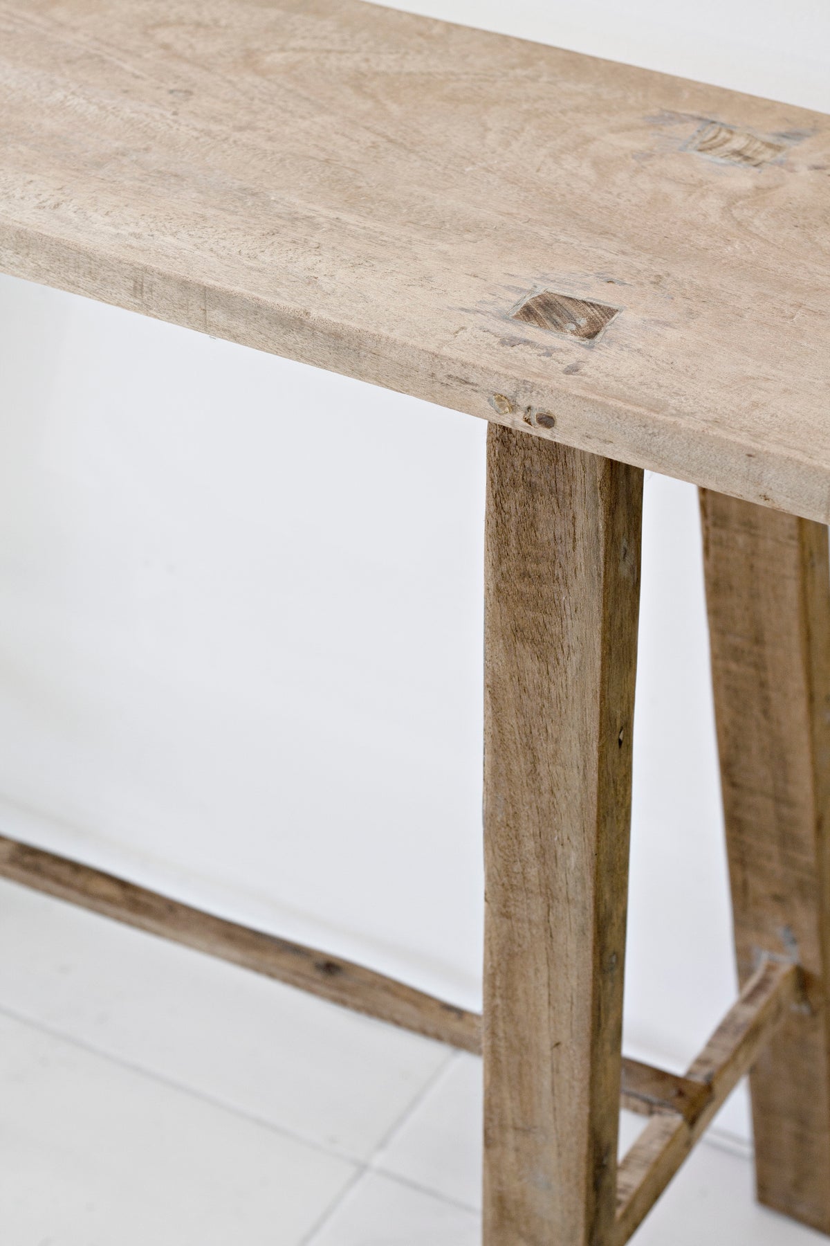 Close up of the recycled teak tabletop edge and leg joint, showing knots in the timber