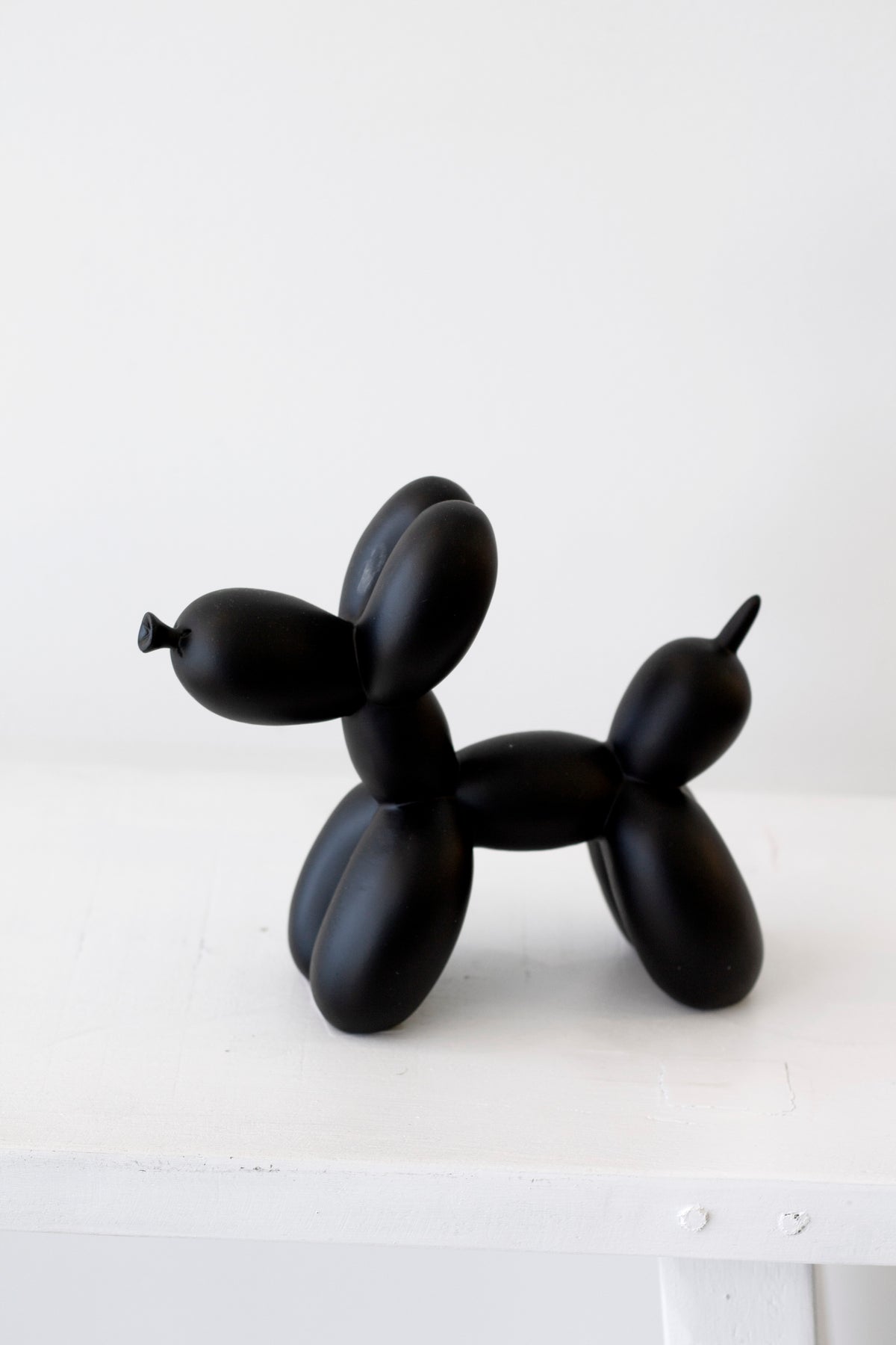 Black ceramic balloon dog sculpture on a white background
