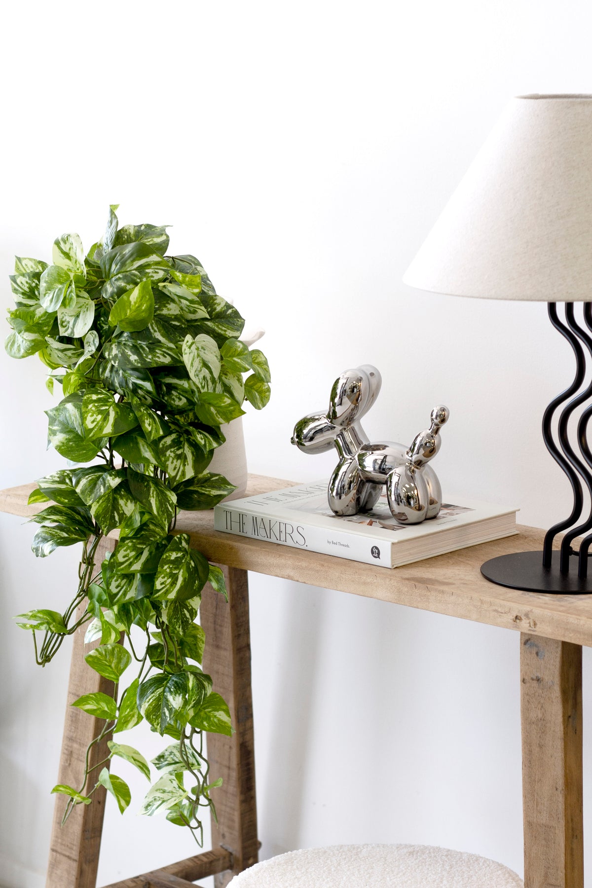 Timber console styled with the trailing pothos, a silver balloon dog and a striped lamp base