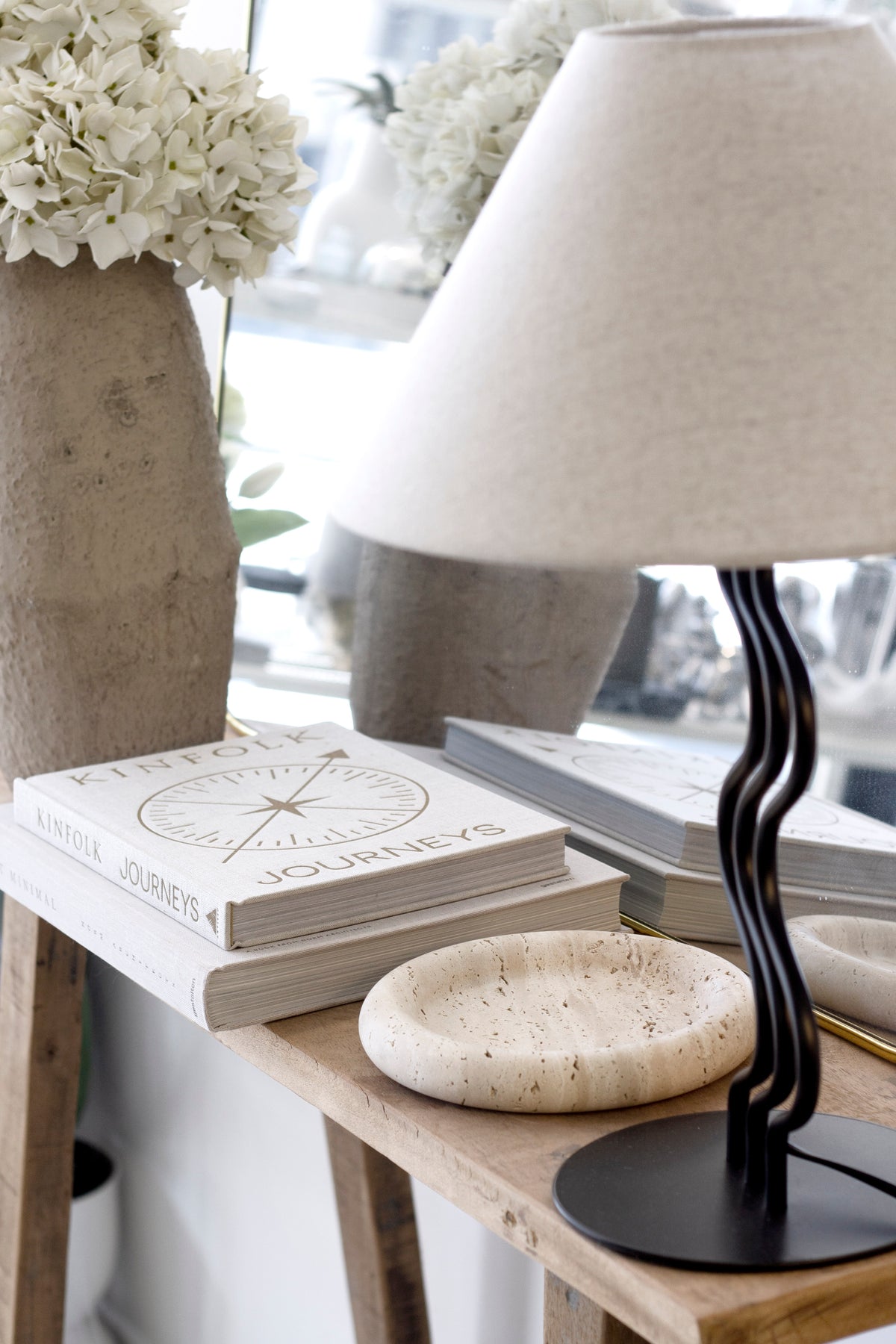Bay Round Tray on a timber console beside a black wavy table lamp and a stack of books