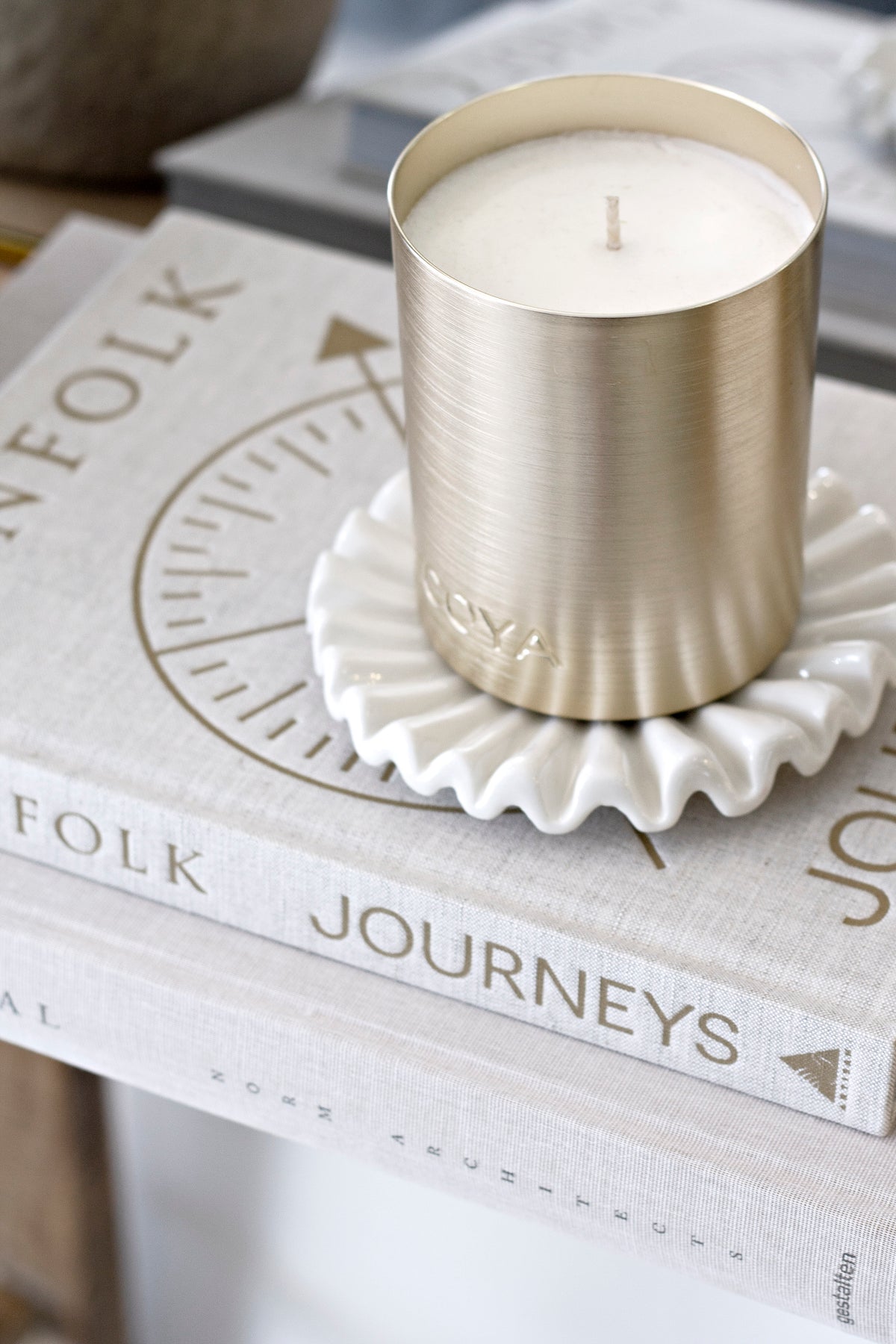 Gold-toned candle on the ruffle tray on a book, close view